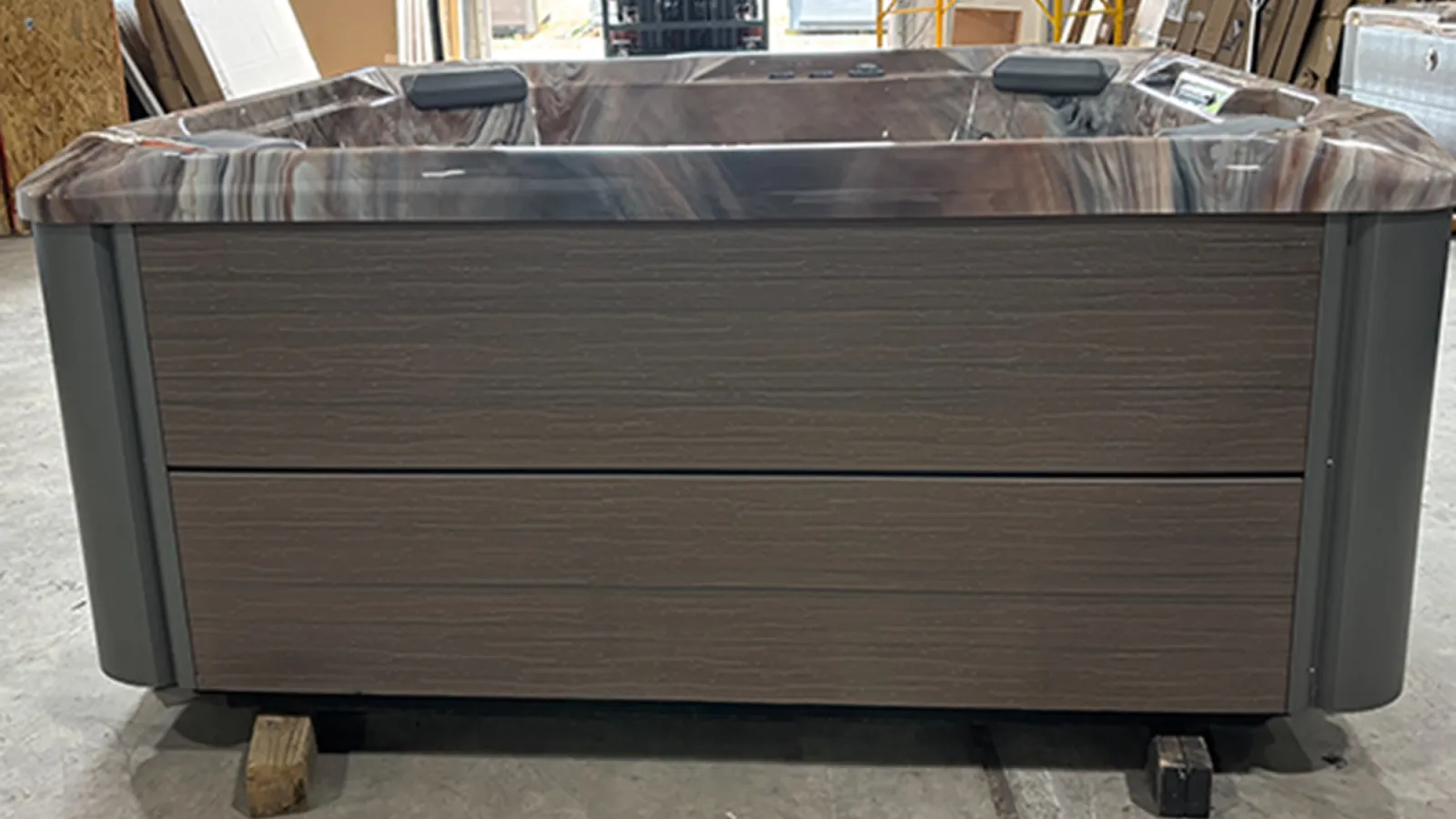 Modern rectangular outdoor hot tub with wood paneling and dark interior in a warehouse setting