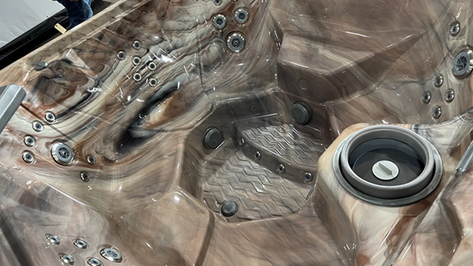 Close-up of a marble-patterned hot tub interior featuring multiple jets and a built-in filter compartment.
