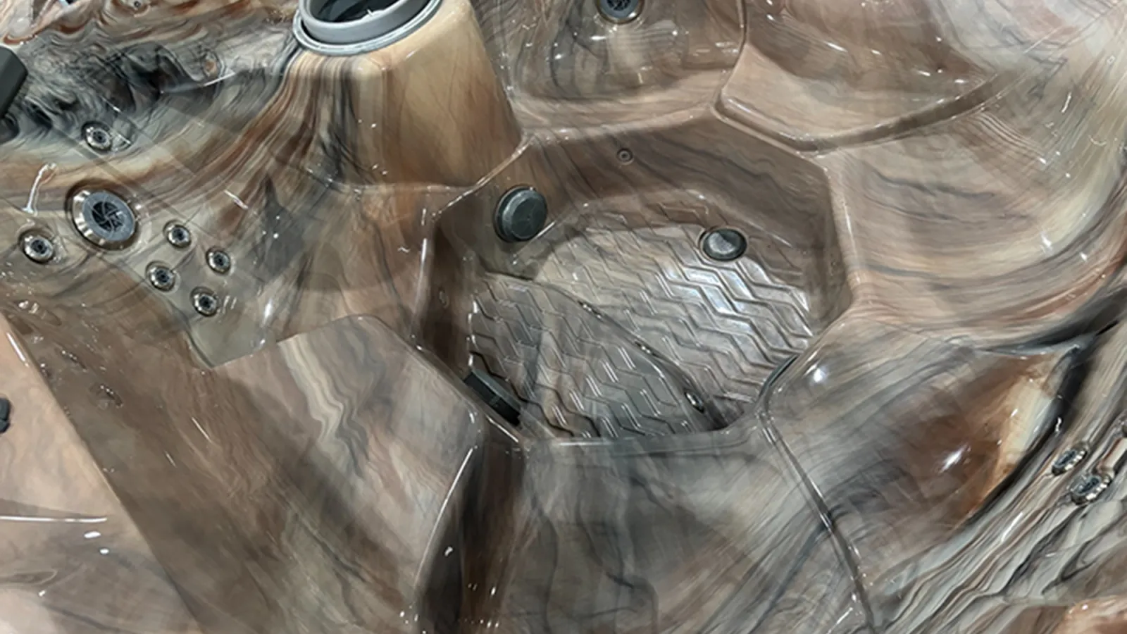 Close-up of a marble-patterned hot tub interior with multiple jets and ergonomic seating areas.
