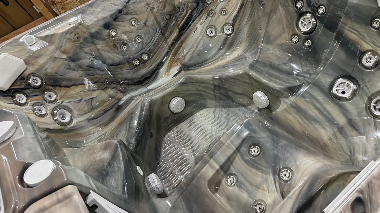 Close-up of a multi-seat hot tub with marble-like textured interior and multiple water jets.