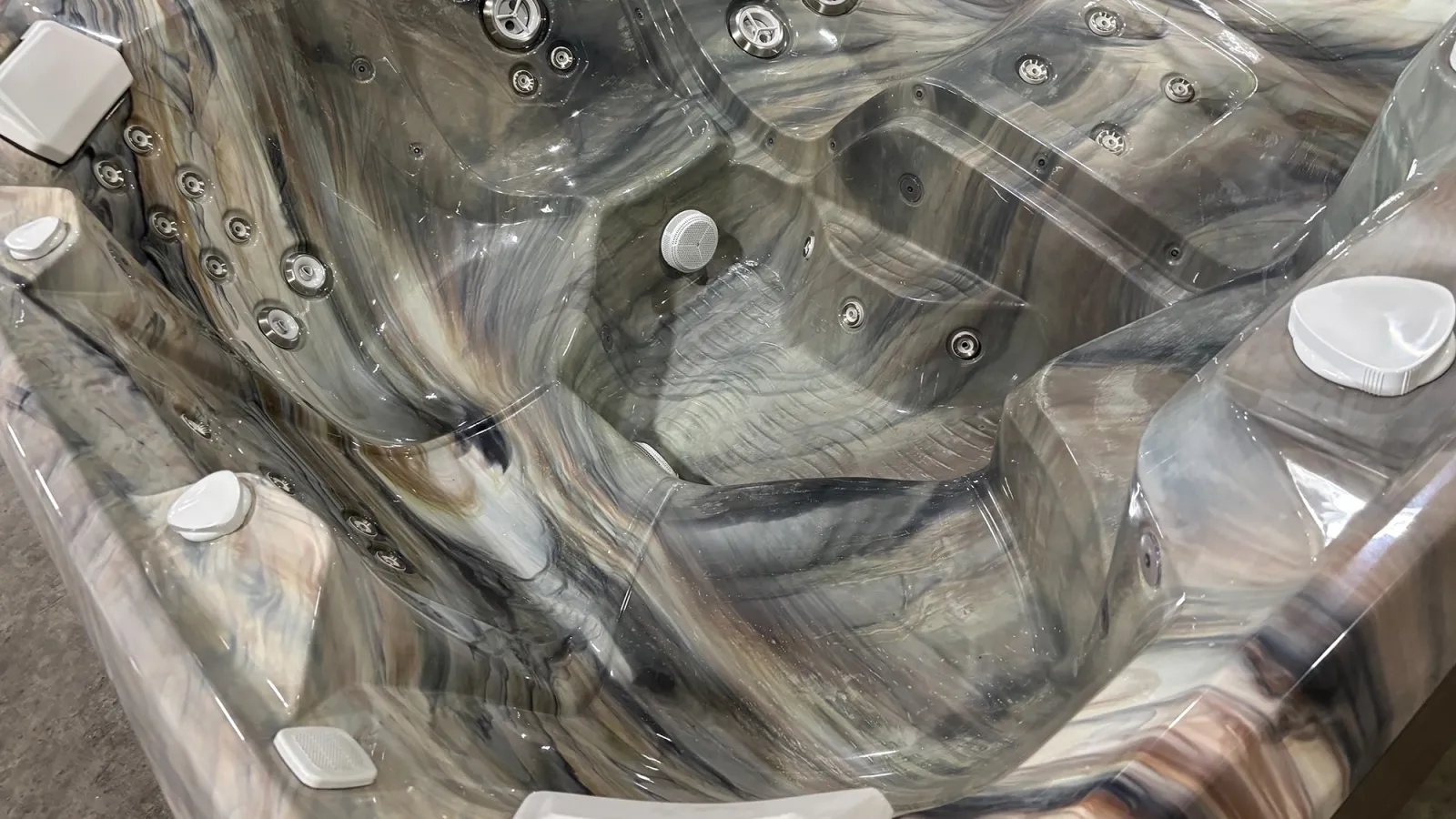 Modern marble-patterned hot tub with multiple jets and ergonomic seating in a showroom.