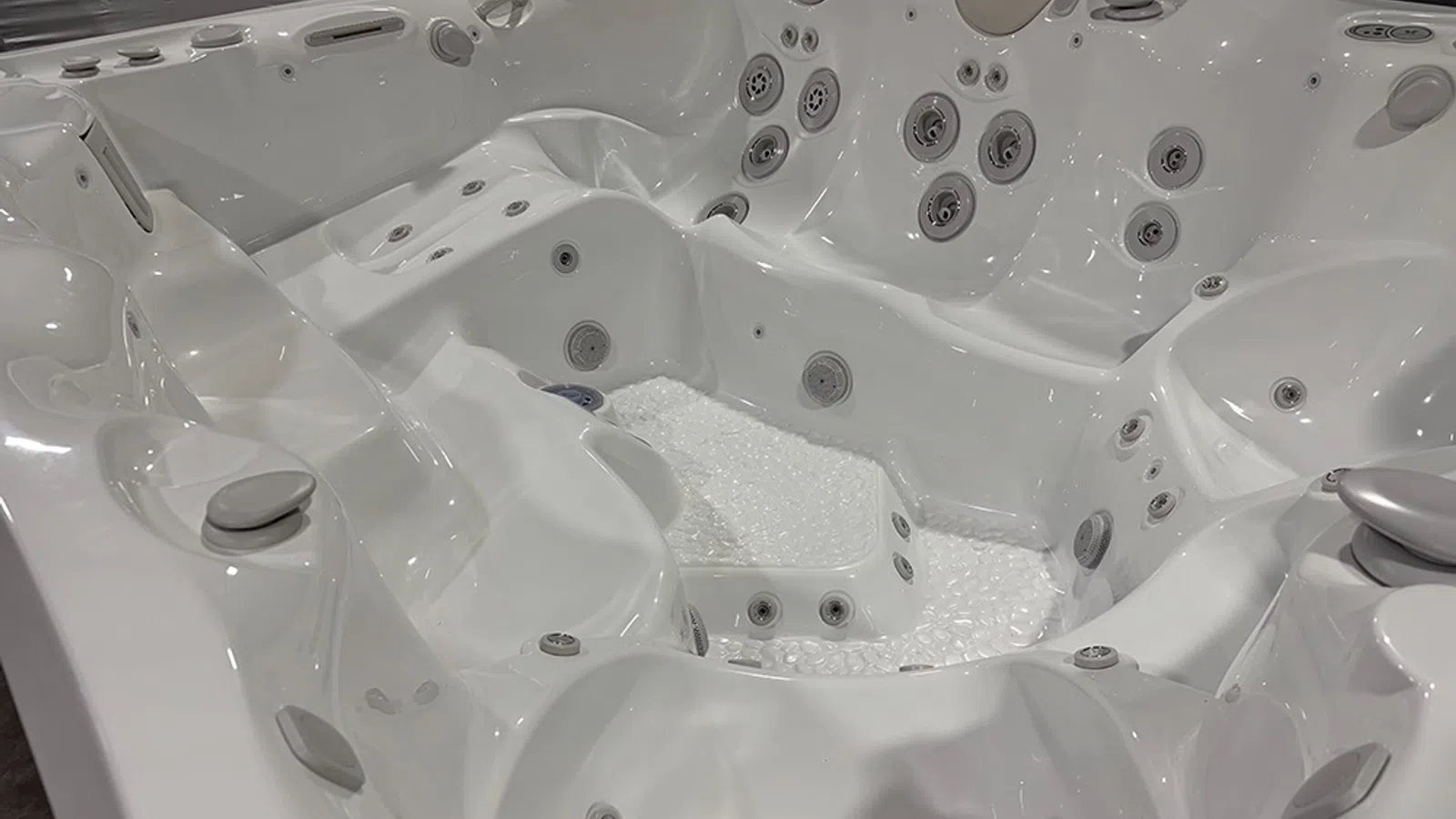 Empty white luxury hot tub with multiple jets and molded seating for relaxation and hydrotherapy.