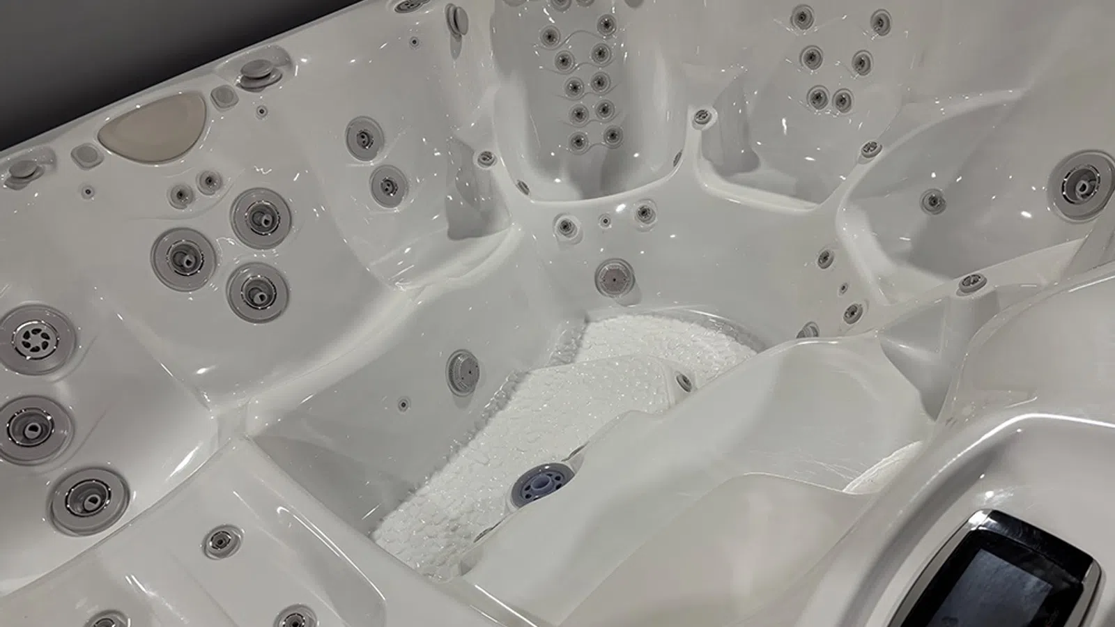Close-up of a white luxury hot tub interior with multiple jets and ergonomic seating.
