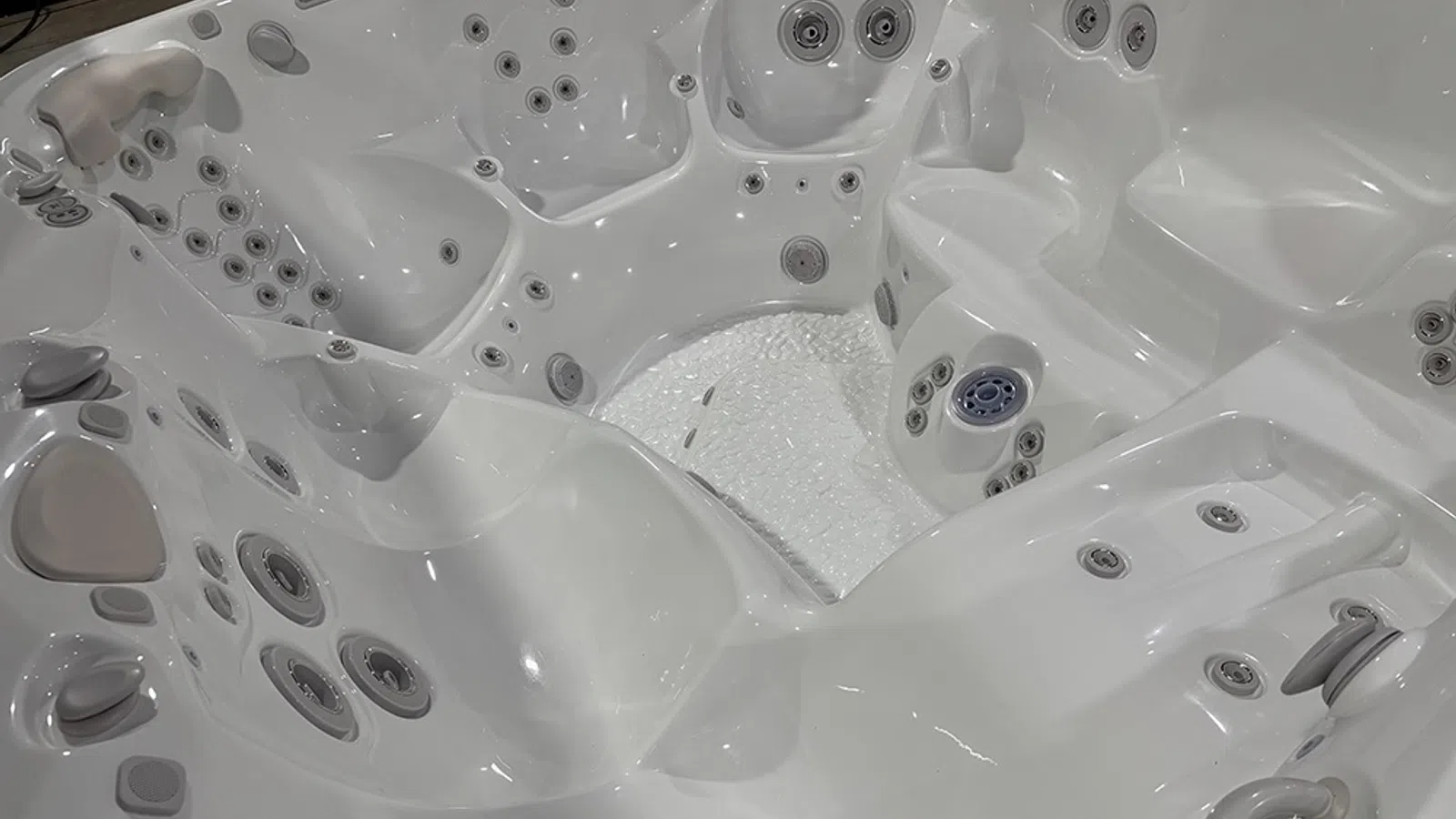 Close-up of a white multi-seat hot tub with multiple water jets and ergonomic seating