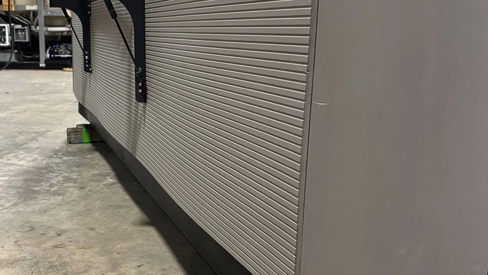 Close-up of a modern, textured office cubicle wall with metal handles and concrete floor in industrial setting.