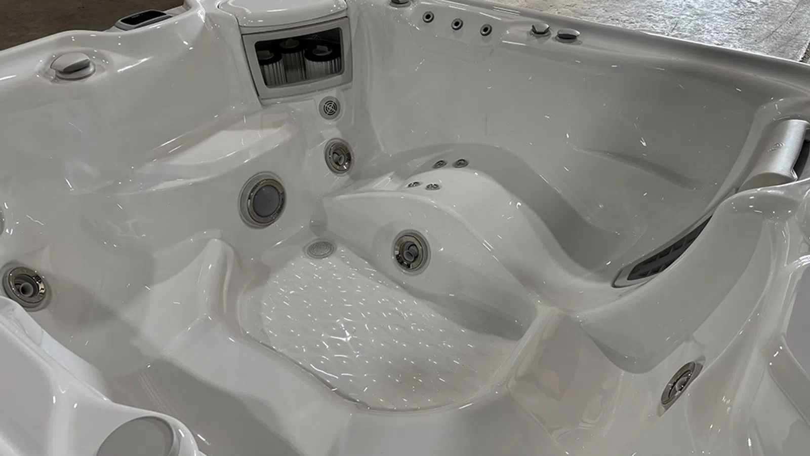 White modern hot tub with multiple jet outlets and contoured seating for spa relaxation indoors.