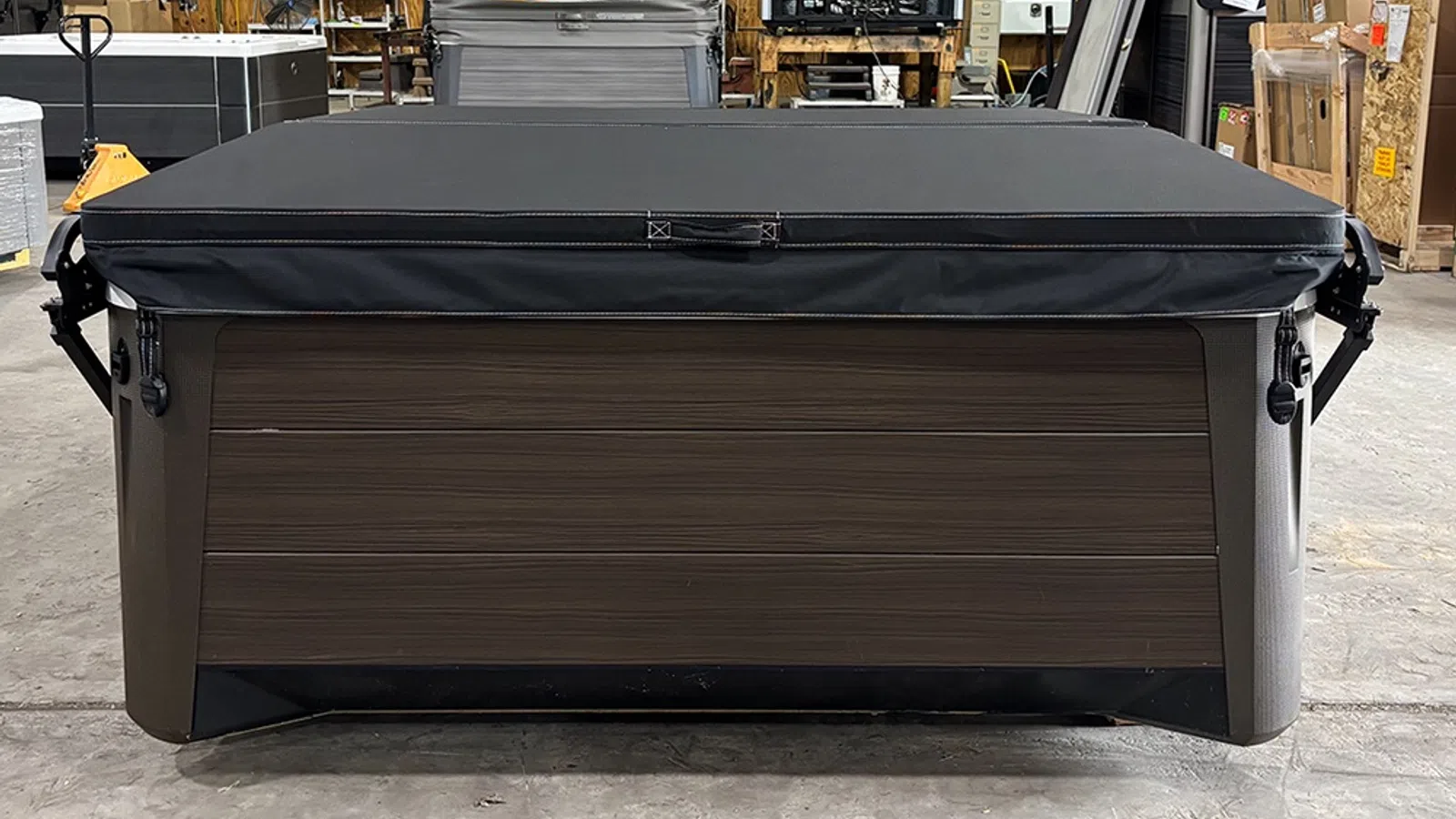 Closed brown hot tub with black cover in a storage warehouse setting.