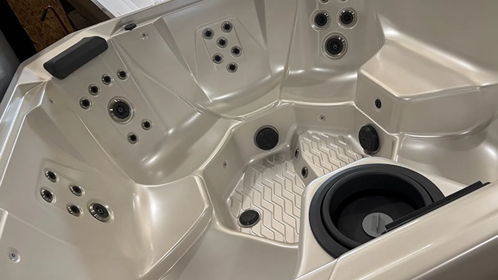 Interior view of a luxury beige hot tub with multiple jet nozzles and seating areas.
