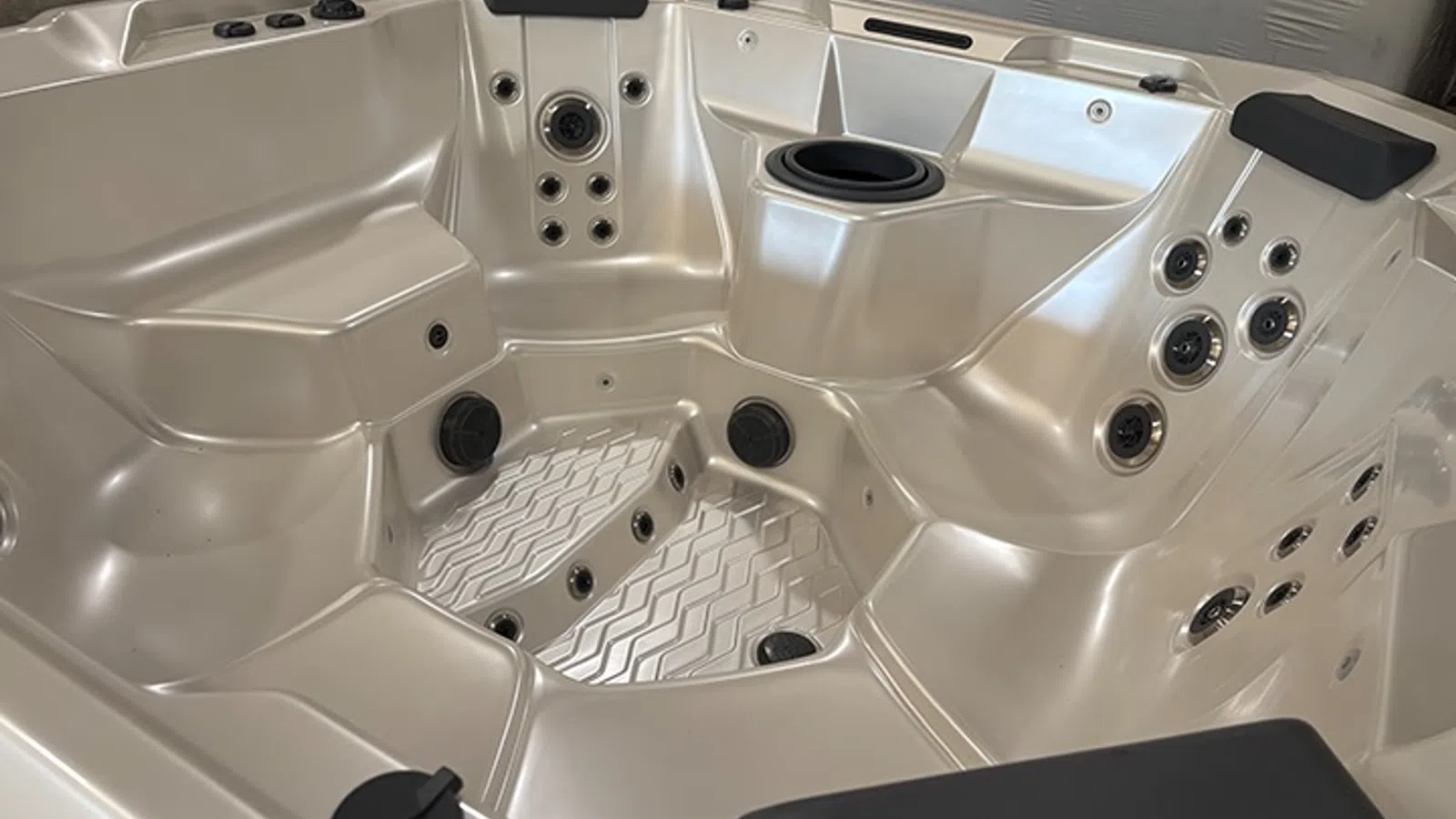 Modern beige hot tub with multiple seats, jets, and built-in cup holders for relaxing hydrotherapy sessions.