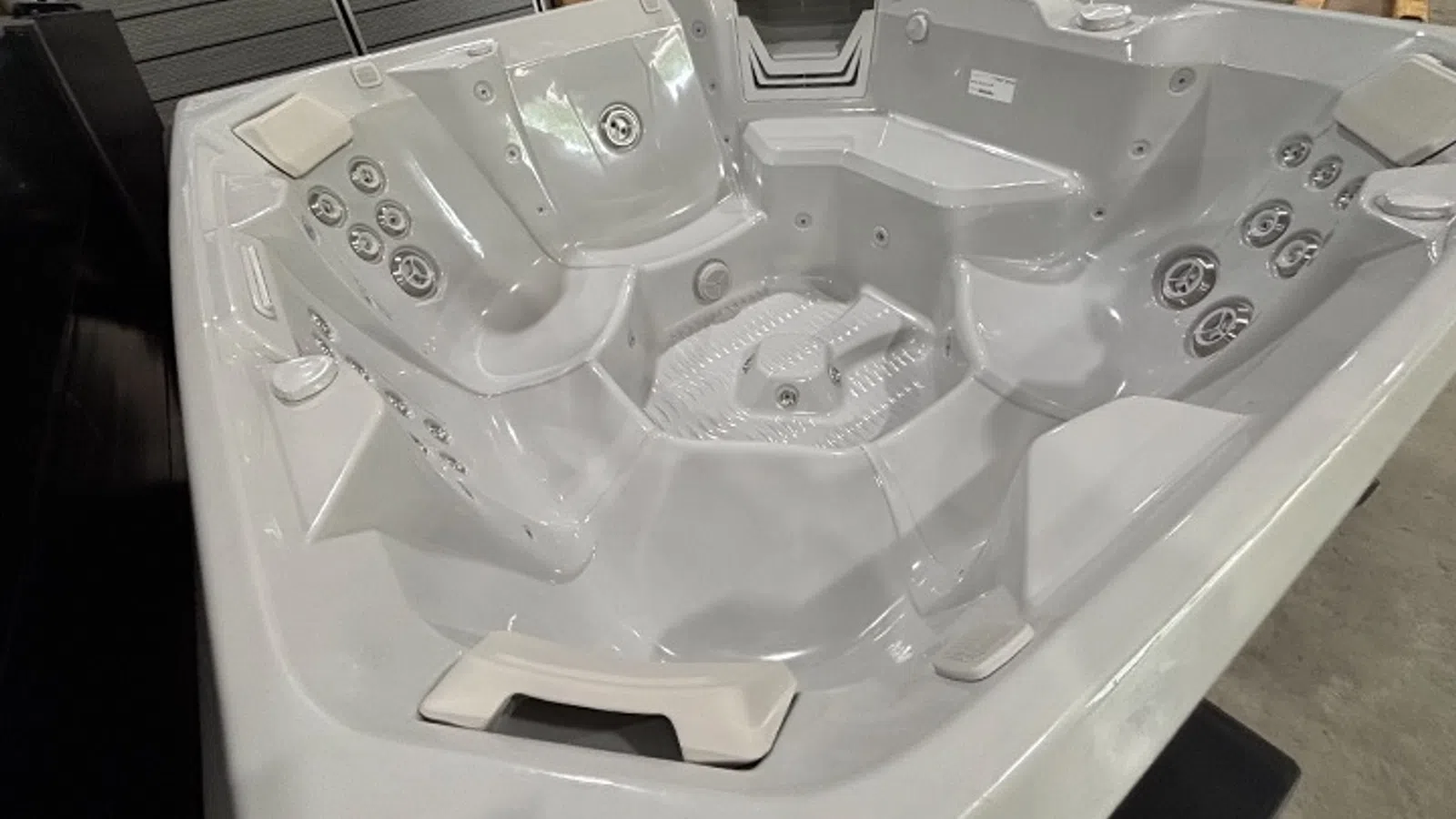 Spacious white multi-seat hot tub with various ergonomic seating and multiple water jets.