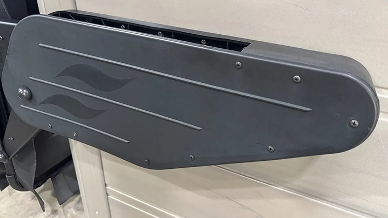 Black plastic armrest with flame decals attached to the side of a chair or vehicle interior.