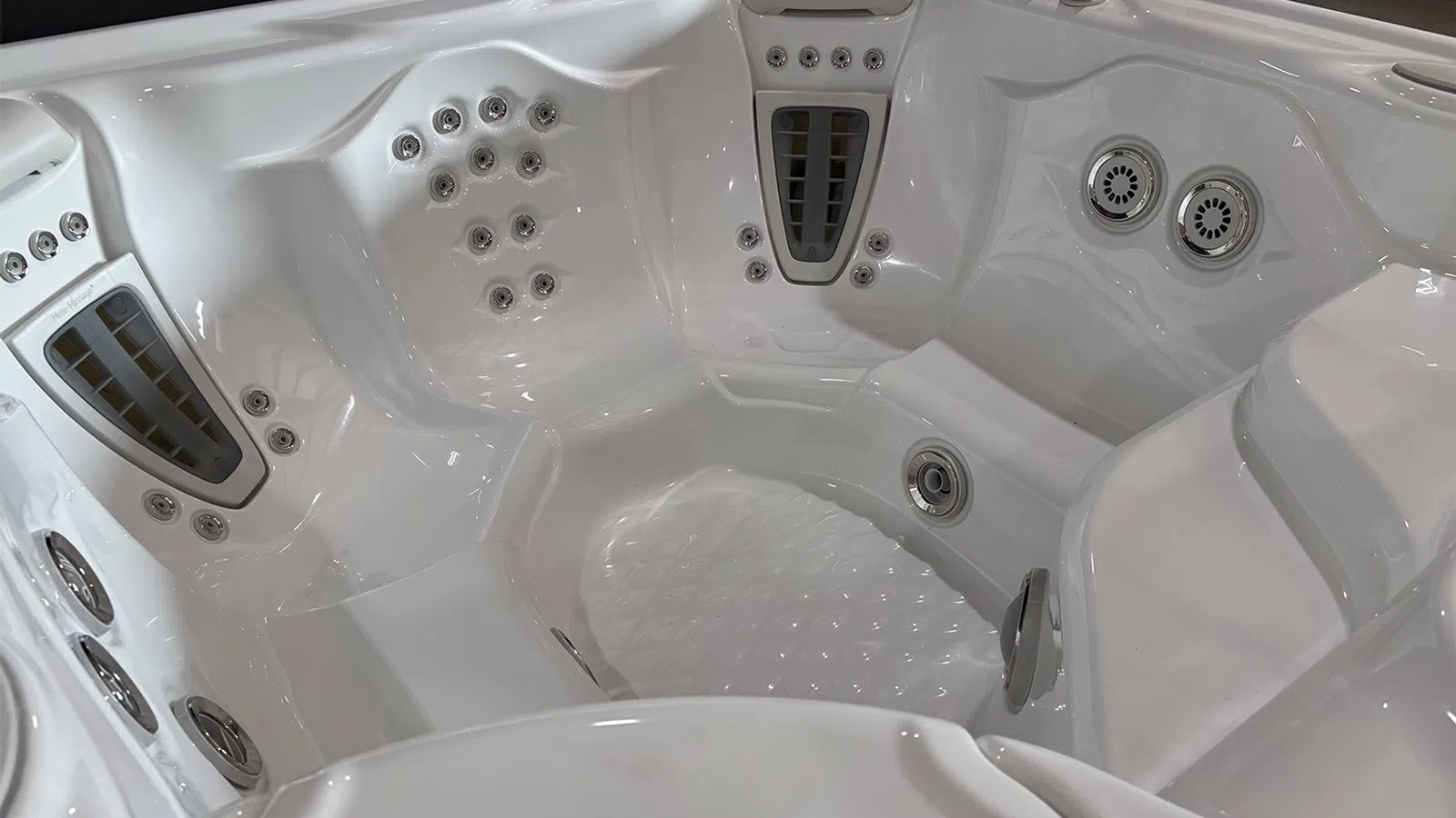 Interior view of a white multi-seat hot tub with various water jets and ergonomic seating areas.