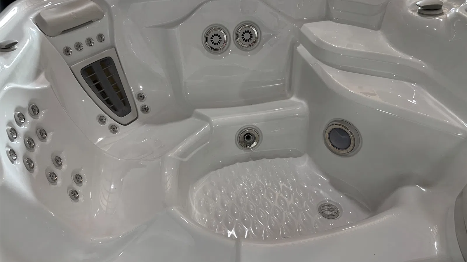 Close-up of a modern white hot tub showcasing multiple hydrotherapy jets and contoured seating.