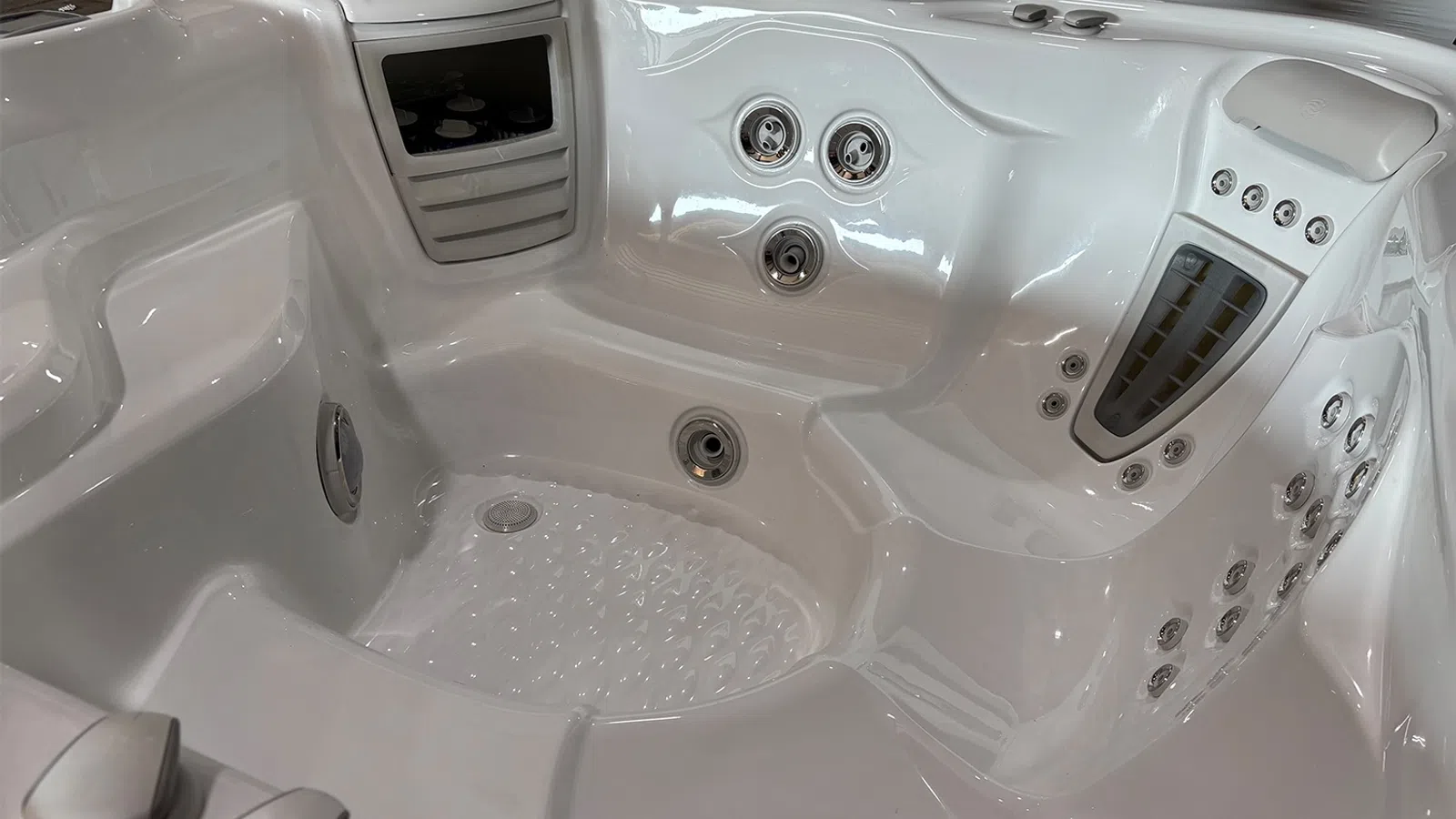 Interior of a clean white jacuzzi hot tub with multiple water jets and seating areas for relaxation.