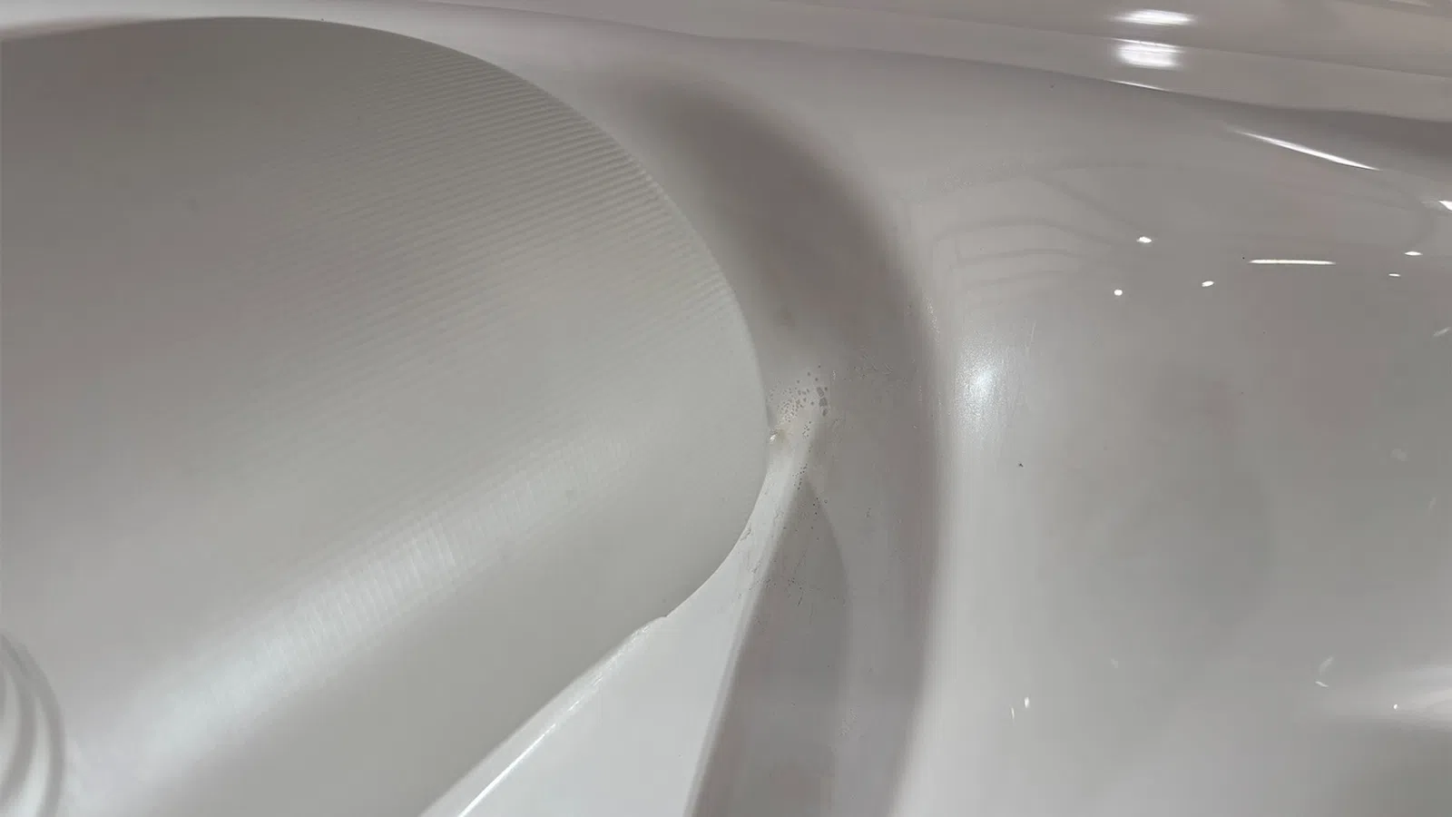 Close-up of a smooth, curved white plastic surface with subtle texture and reflections.