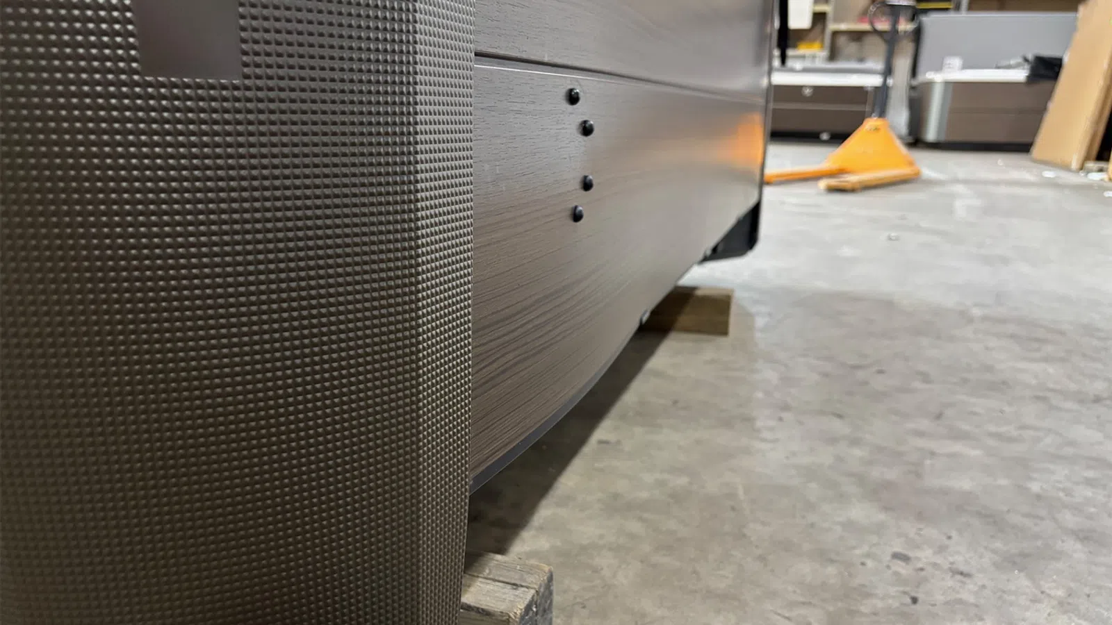 Close-up of textured and brushed metal surfaces on industrial equipment in a warehouse setting with scattered tools.