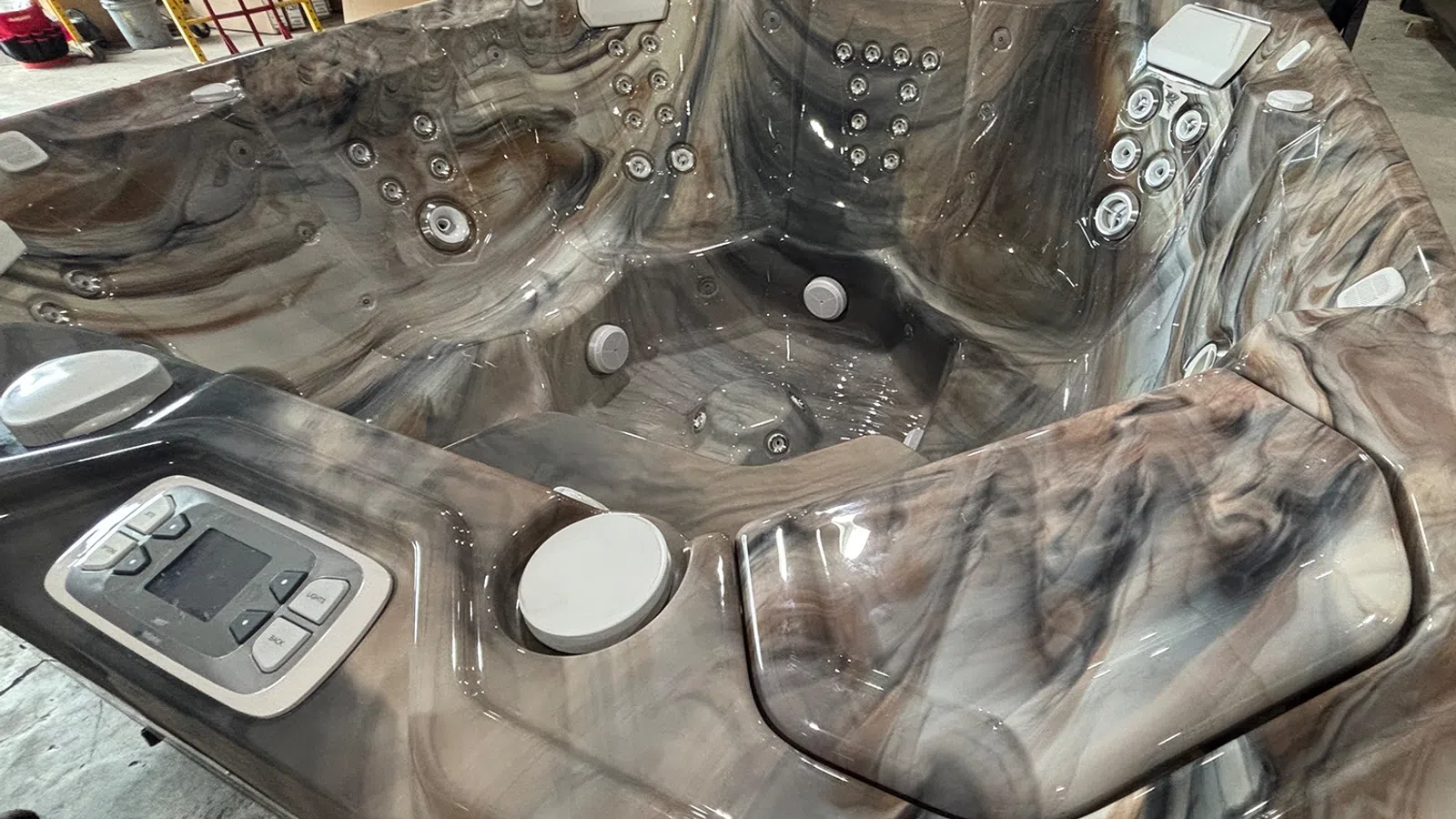 Modern marble design hot tub with multiple jets, headrests, and digital control panel indoors.