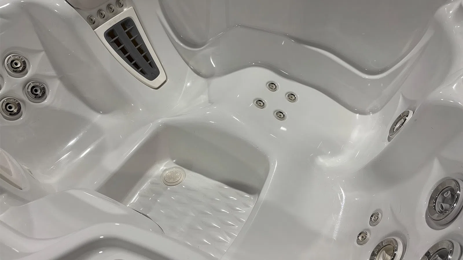 Close-up of an empty white jacuzzi tub showing multiple water jets and contoured seating areas.