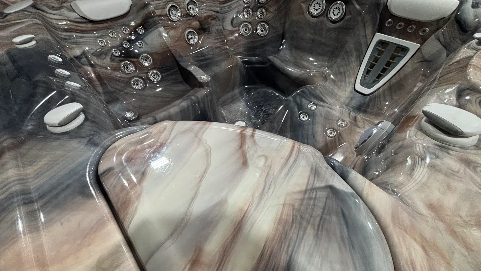 Close-up of a marble-textured hot tub interior with multiple water jets and padded headrests.