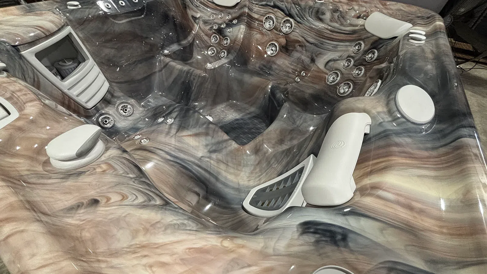 Close-up of a marbled luxury hot tub interior with seating, jets, and headrests in a muted color palette.