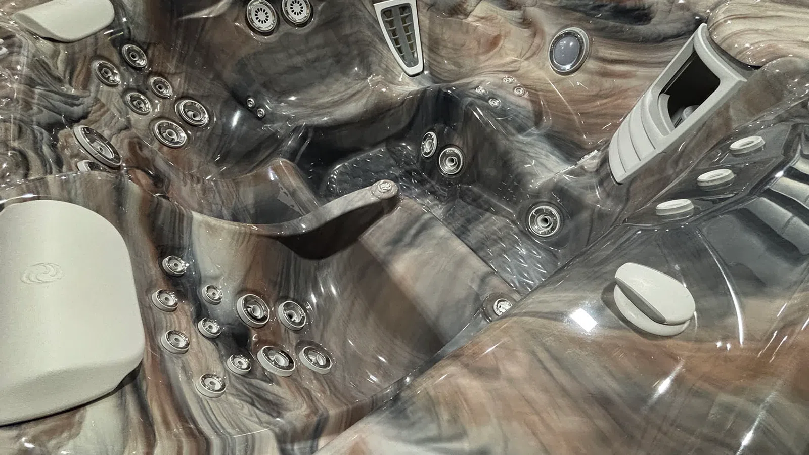Close-up of a luxury hot tub interior featuring multiple water jets and ergonomic seating in marbled finish.
