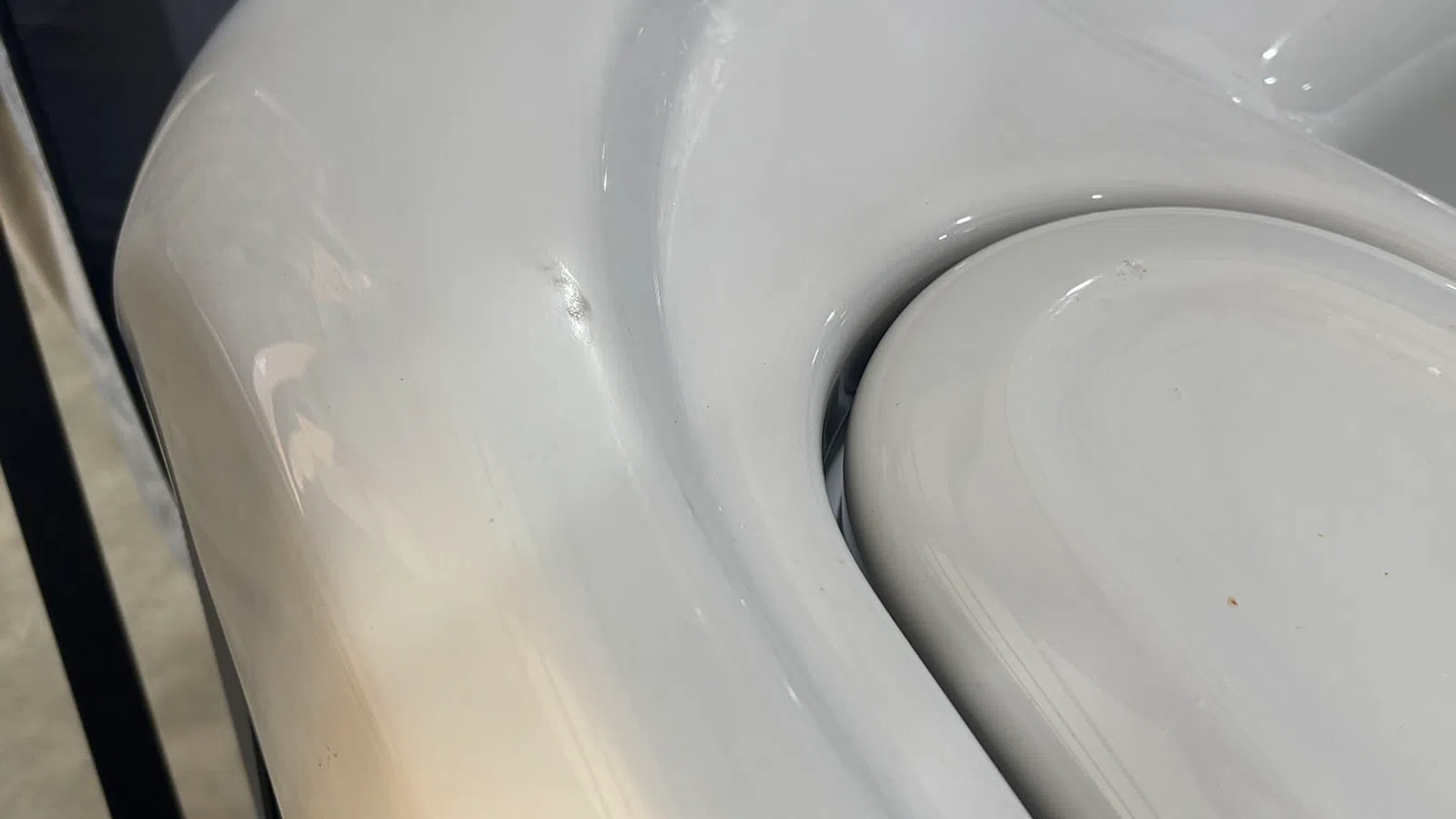 Close-up of a smooth, white porcelain surface with curved edges and shiny finish under natural light