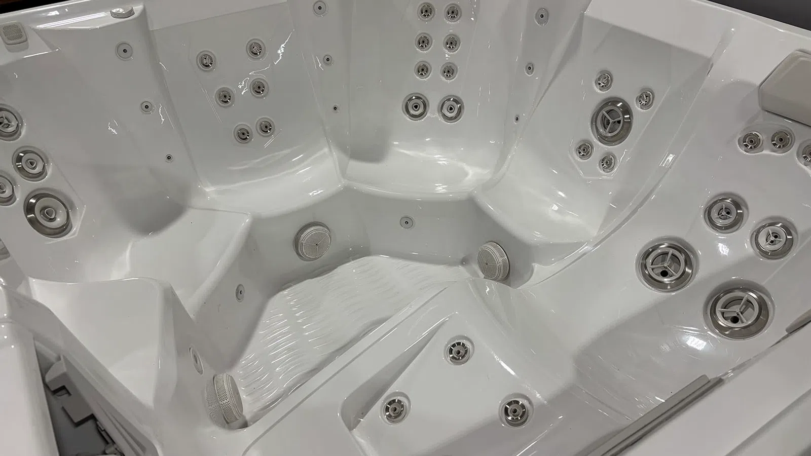 Close-up of a white multi-seat hot tub with numerous water jets and ergonomic seating areas.