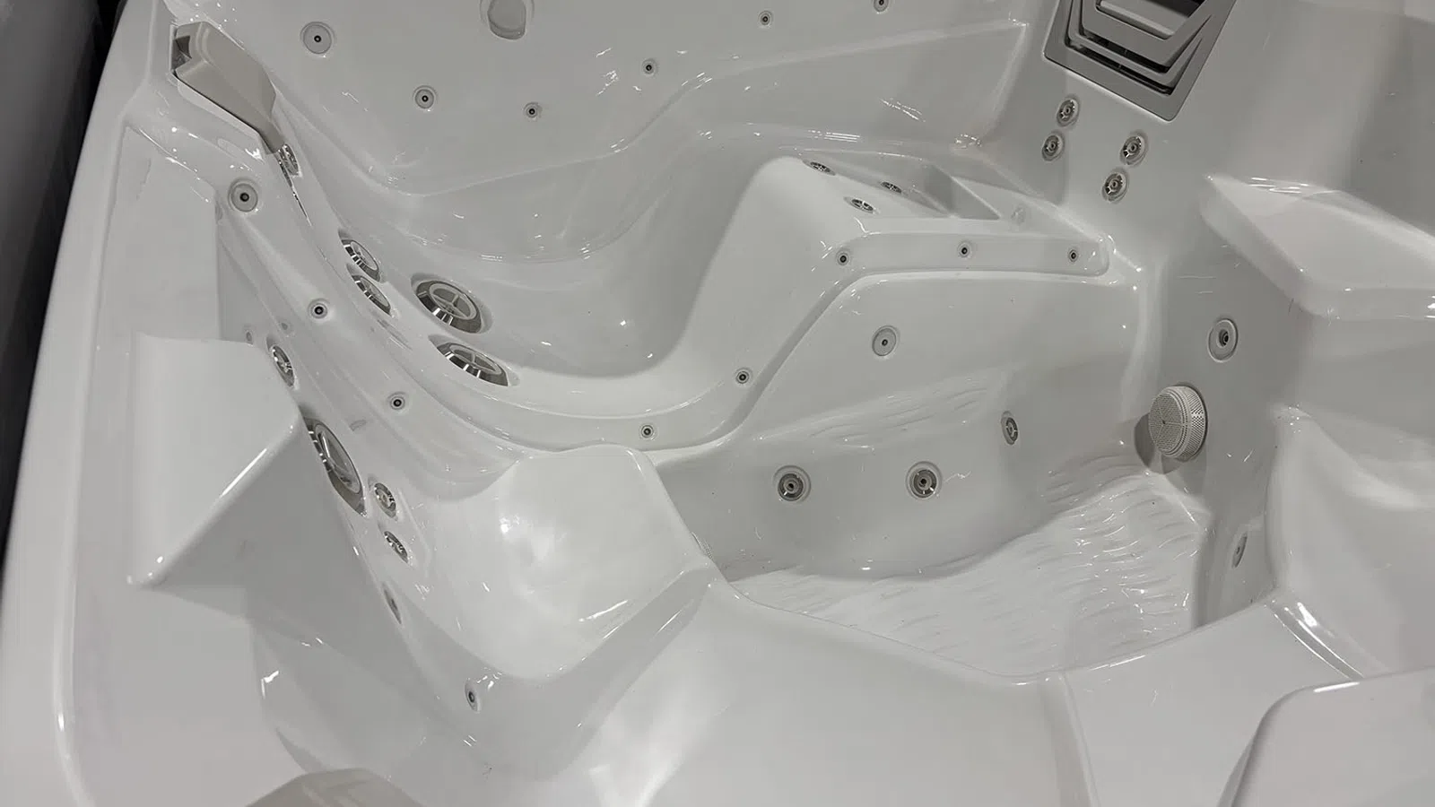 White multi-seat hot tub with built-in jets and headrests for a relaxing spa experience indoors or outdoors.