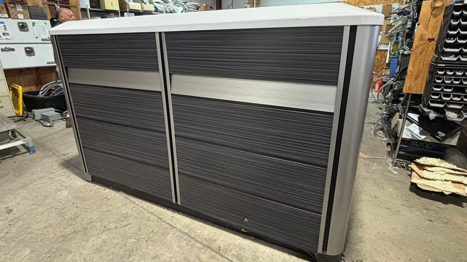 Modern black and gray reception desk with metallic accents in a warehouse setting.