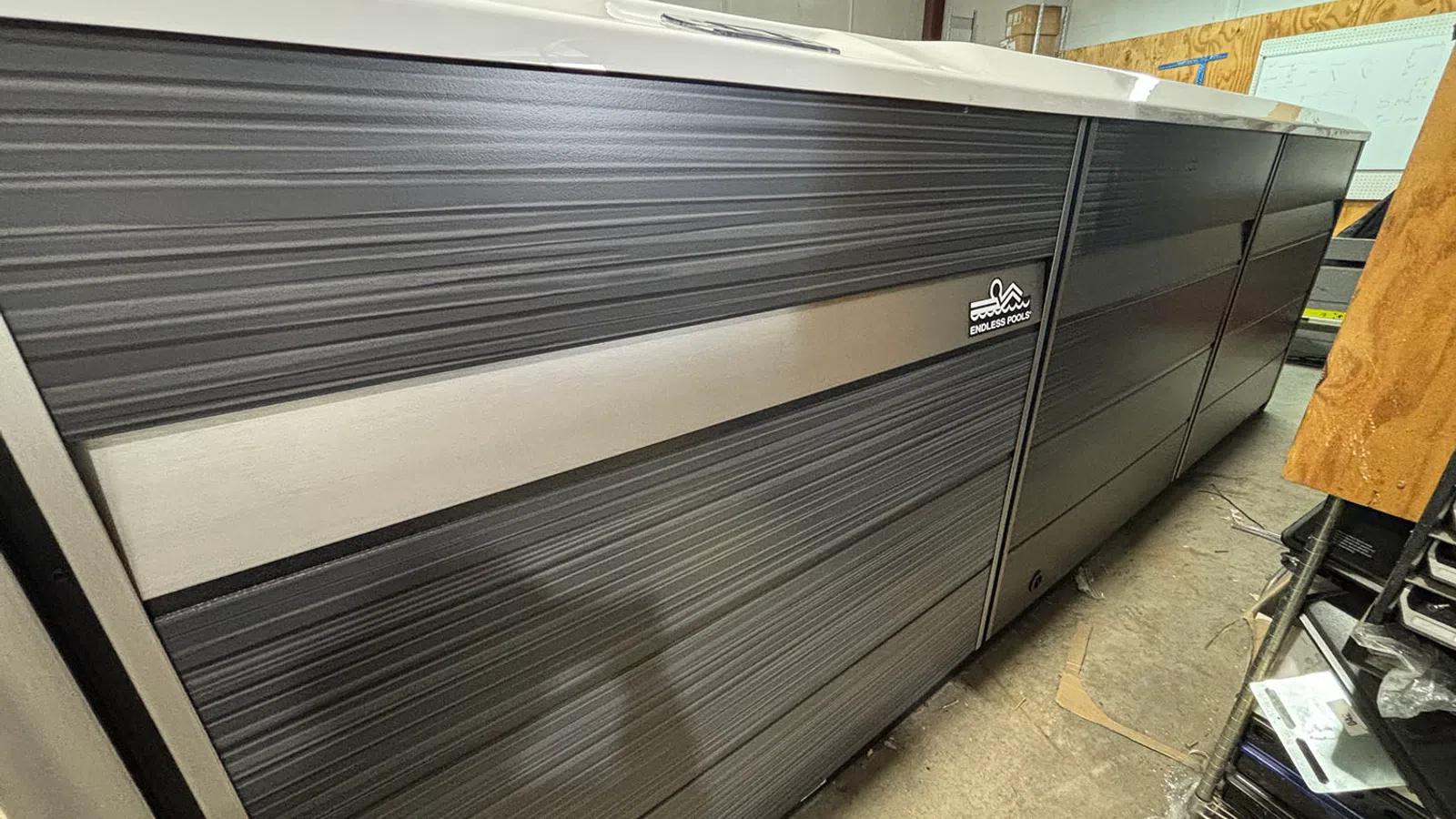 Long gray textured cabinet with a horizontal silver stripe and Endless Pools logo, photographed indoors.