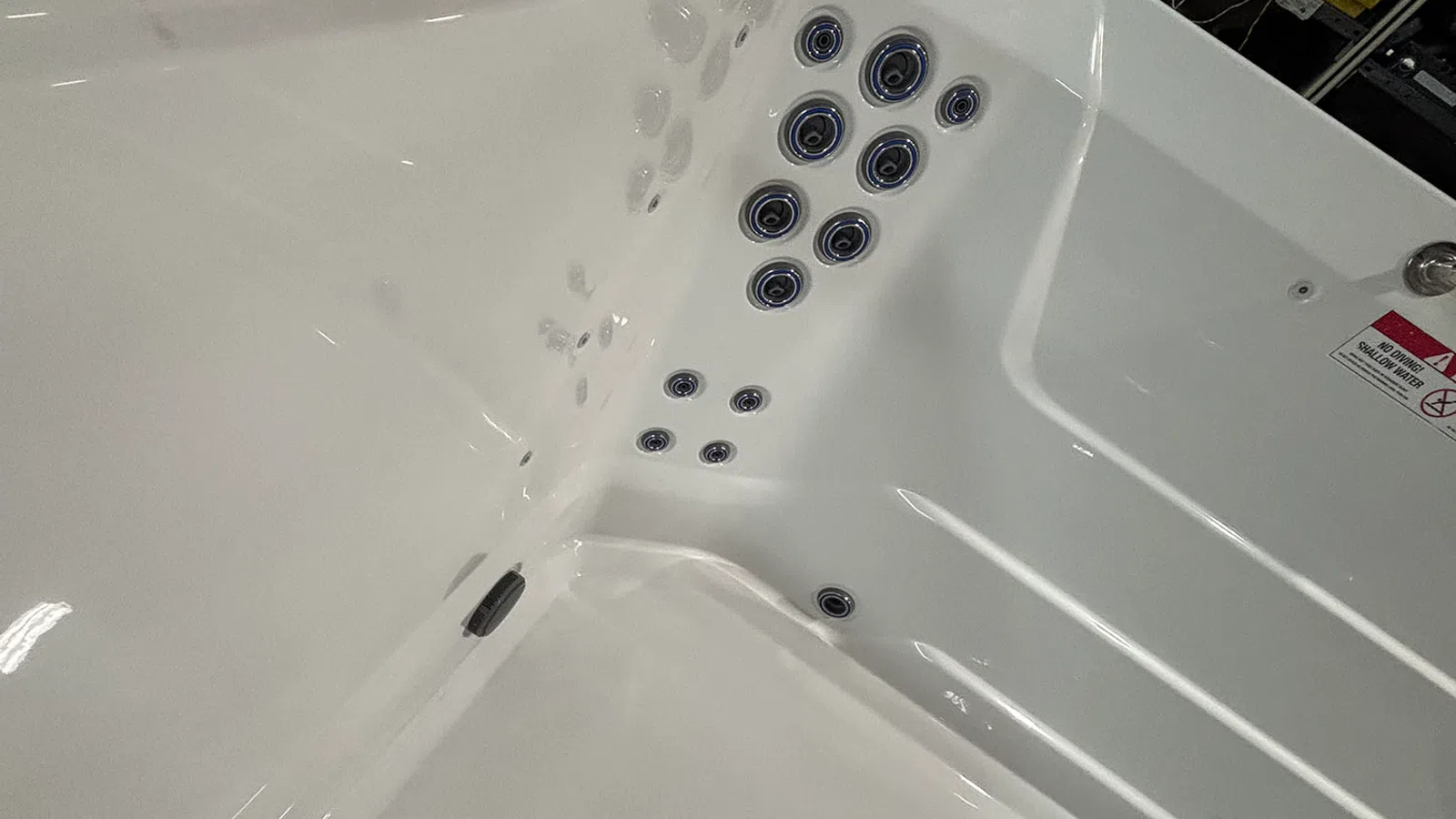 Close-up of white hot tub interior showing multiple black and silver water jets arranged on the walls.