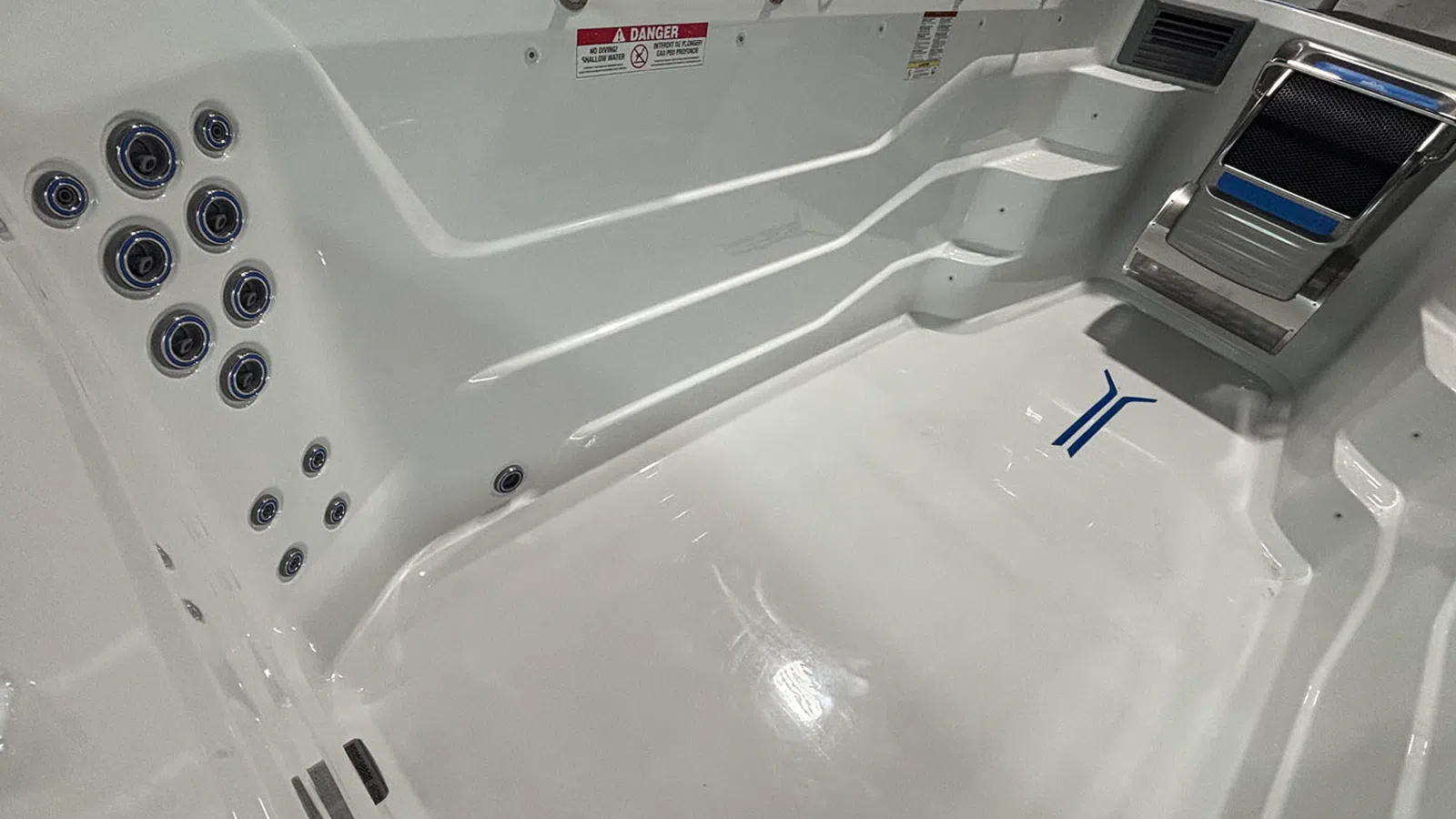 White swim spa with multiple water jets, built-in steps, and a metal handle on one side.