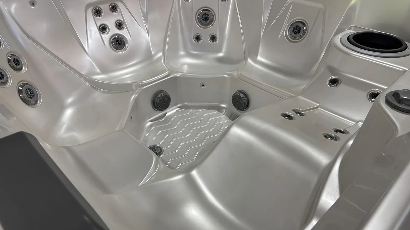 Empty silver spa hot tub interior with multiple jet nozzles and contoured seating for relaxation.