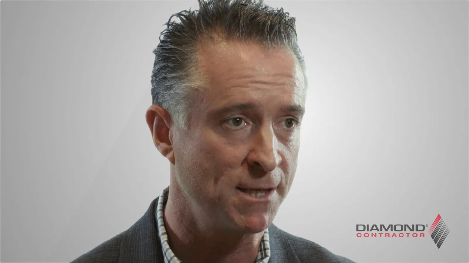 Man in business attire speaking against a plain background with Diamond Contractor logo visible.