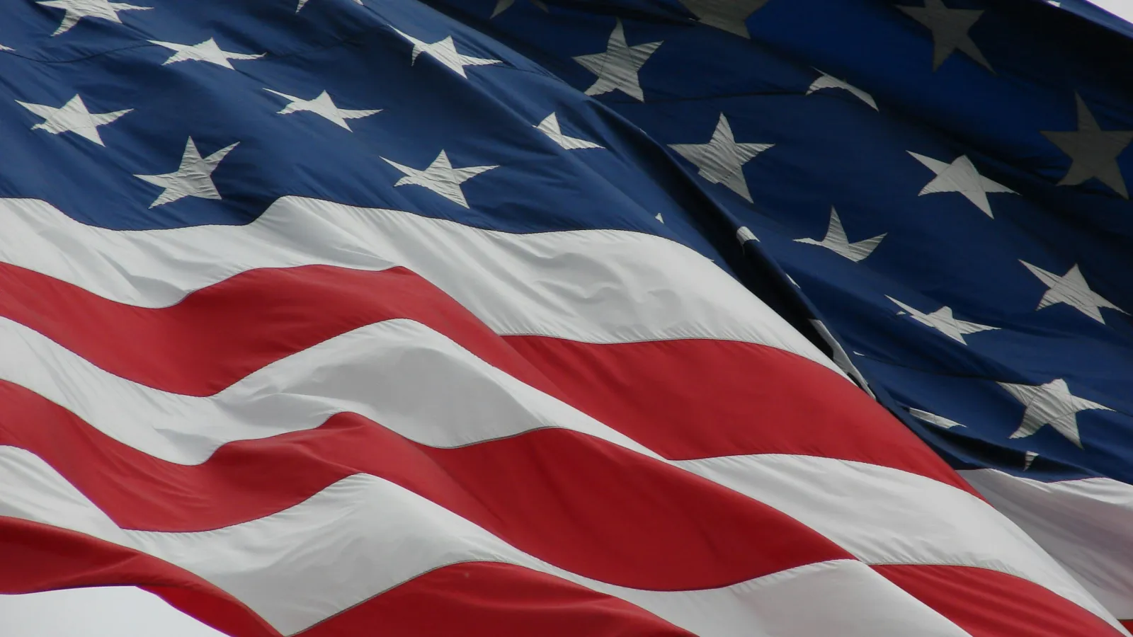Close-up of American flag waving showing red and white stripes and white stars on blue field