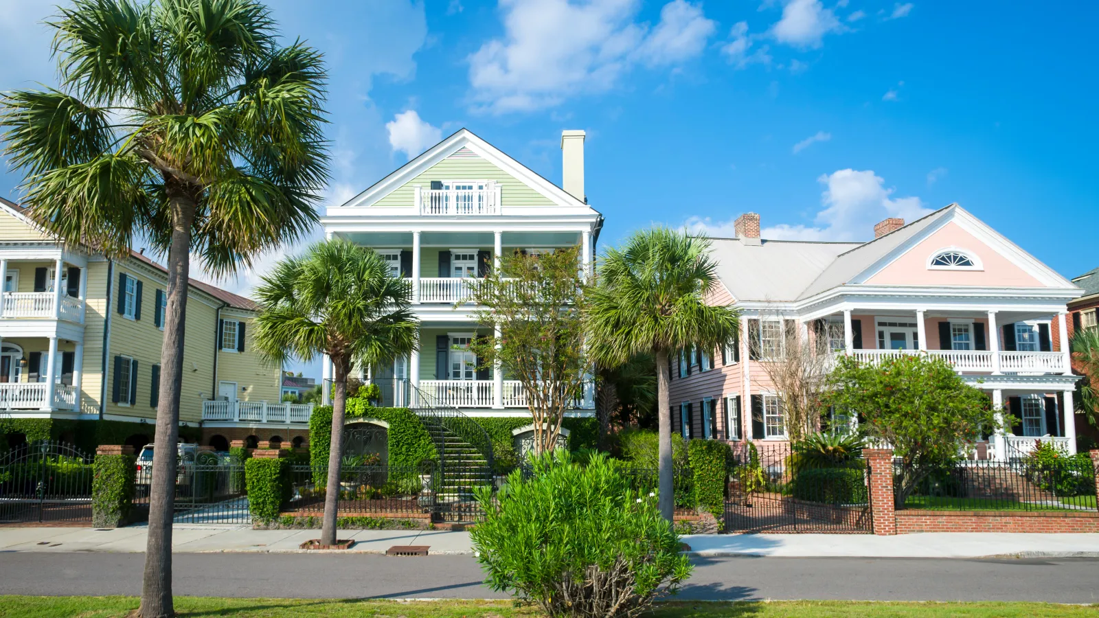 Colorful coastal-style houses with palm trees and blue sky in a sunny neighborhood street