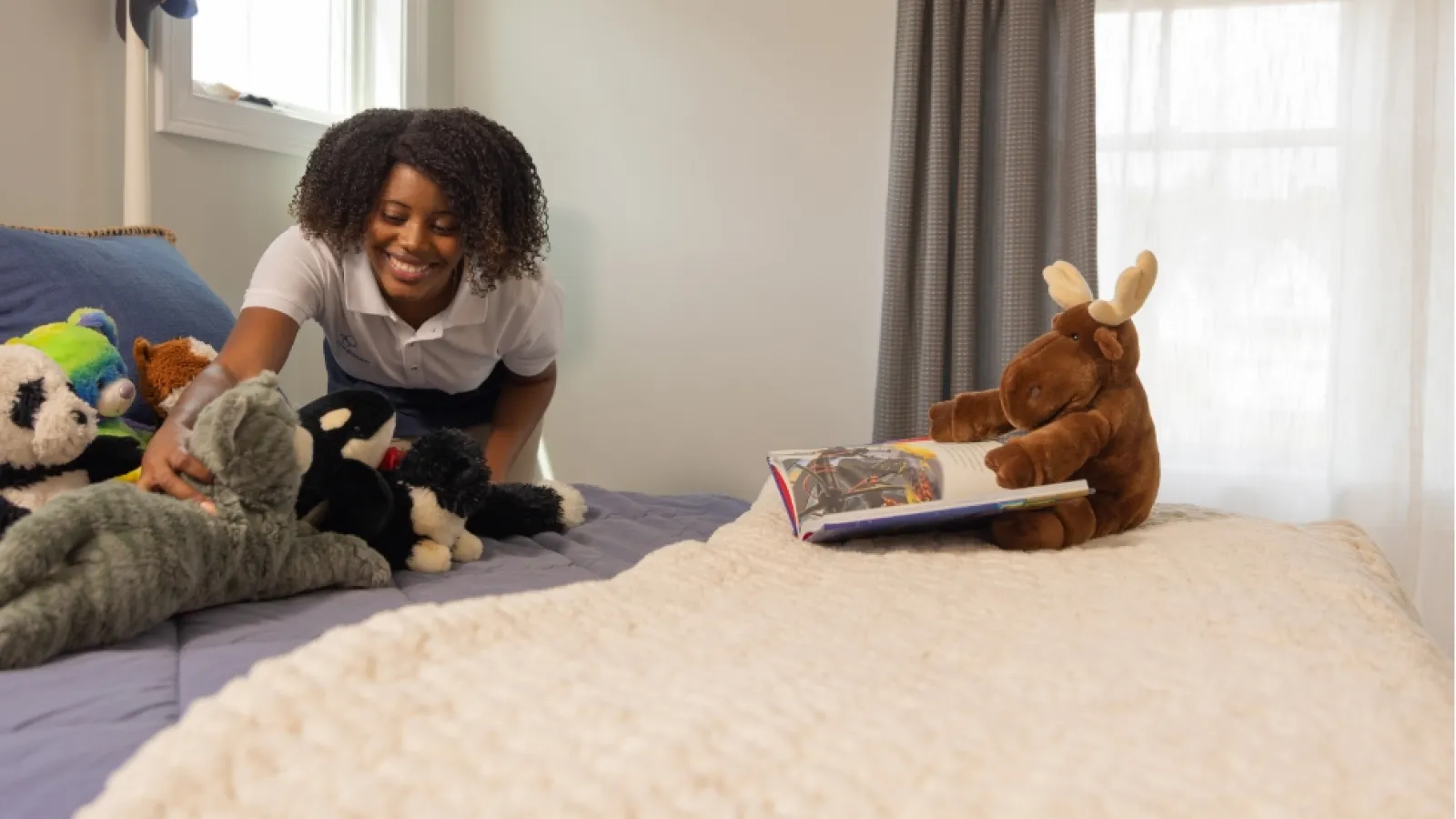 a person reading a book on a bed with stuffed animals