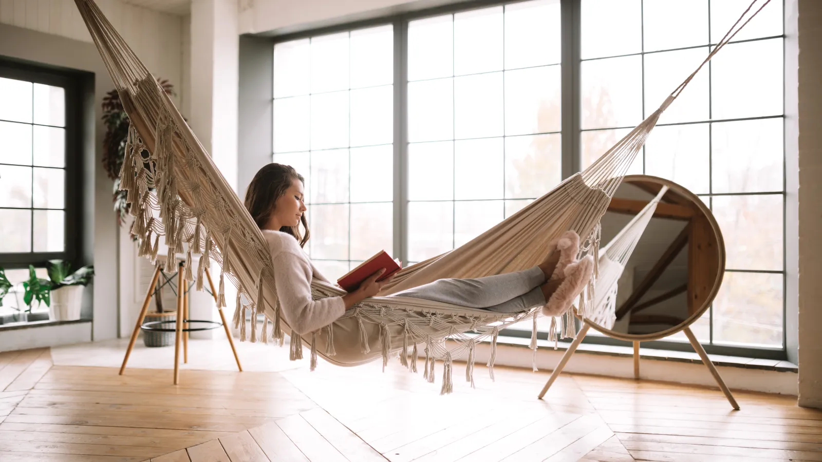 a person sitting in a hammock reading a book