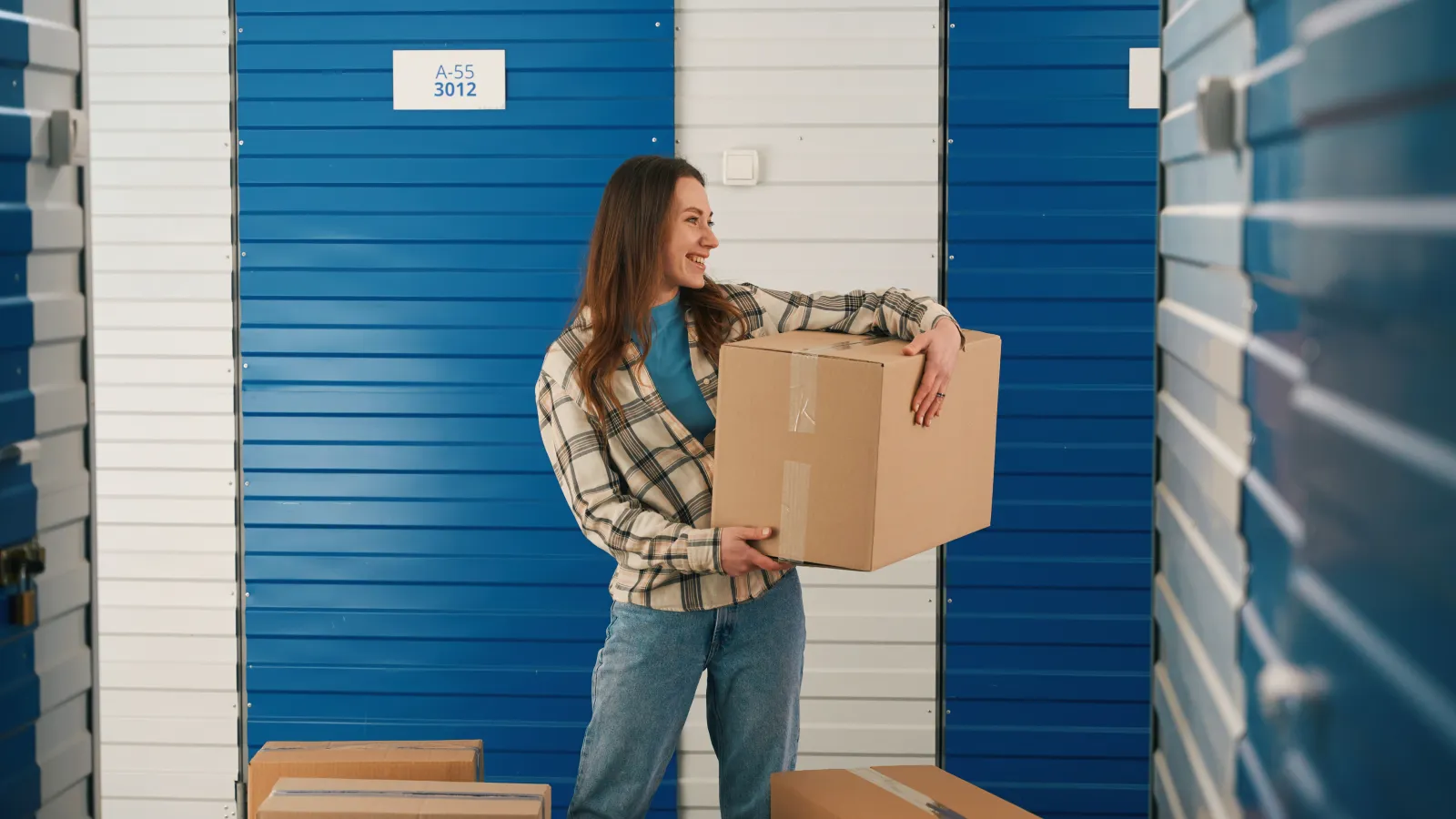 lady with big cardboard boxes outside small indoor storage unit