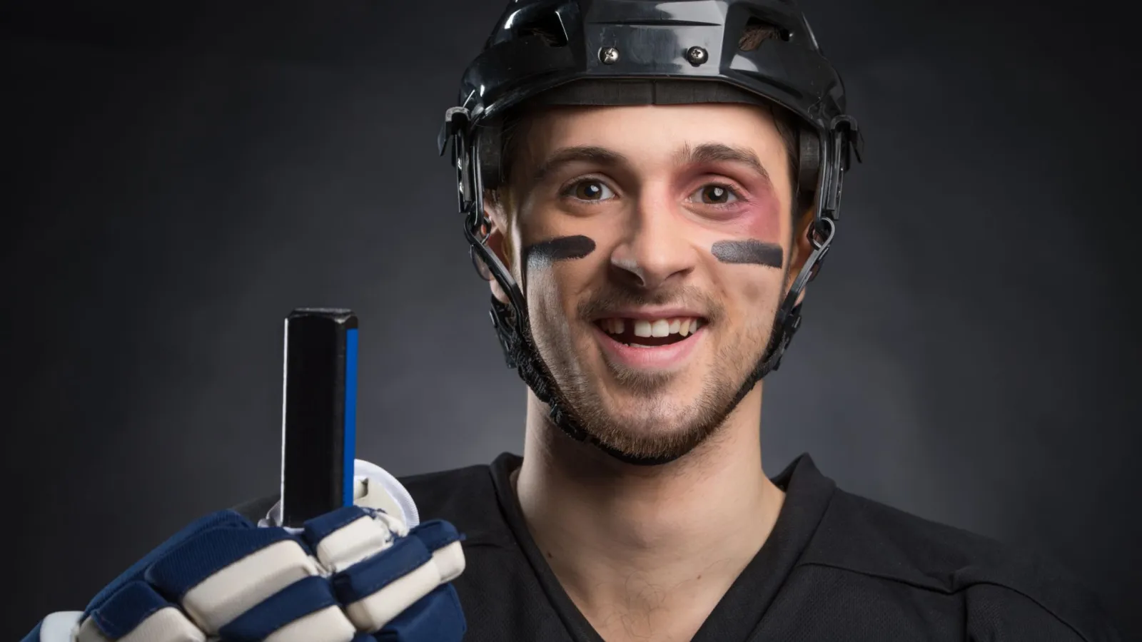 hockey player smiling holding a hockey stick