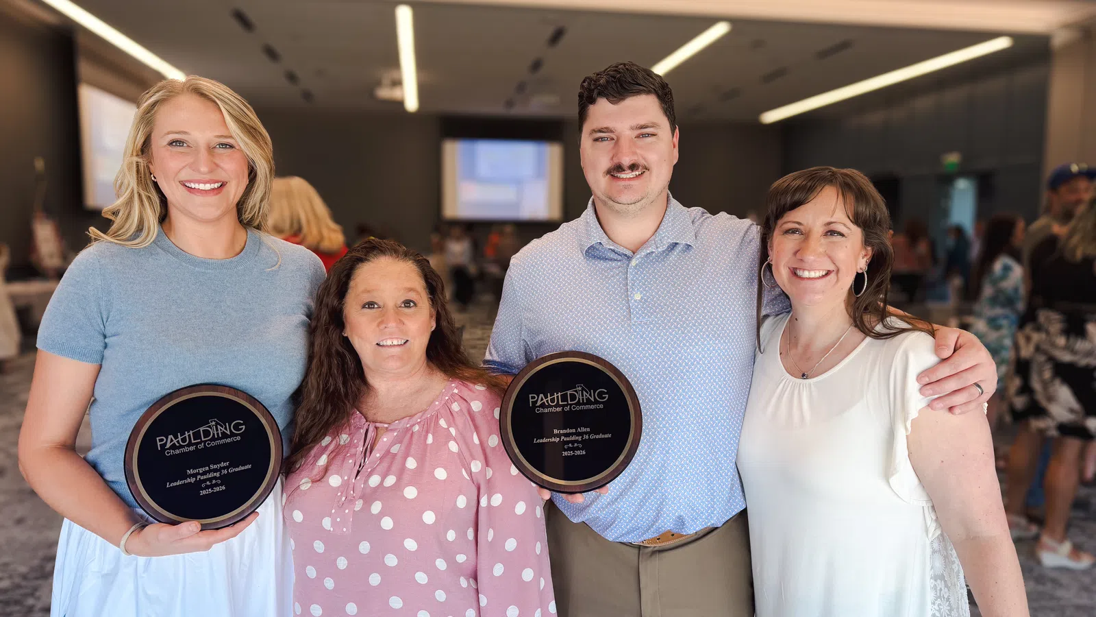 Four smiling people at an awards event holding Paulding Chamber of Commerce recognition plaques indoors.