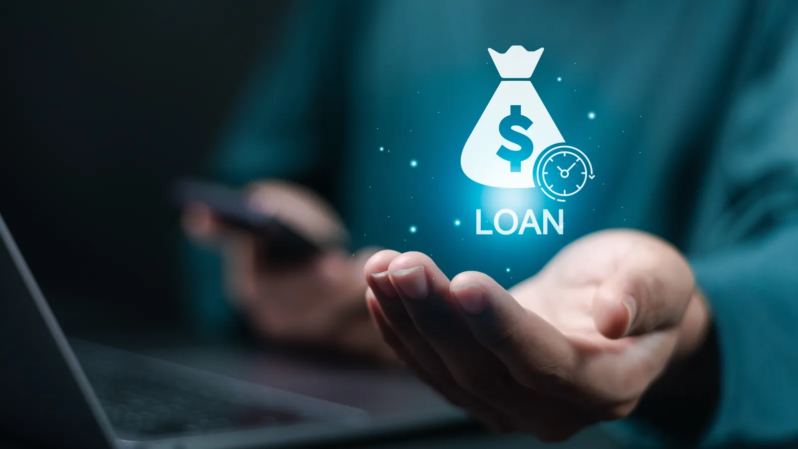 Person holding glowing loan icon with money bag and clock above laptop keyboard on dark background