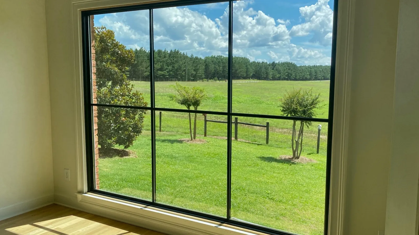 a window with a view of a field and trees