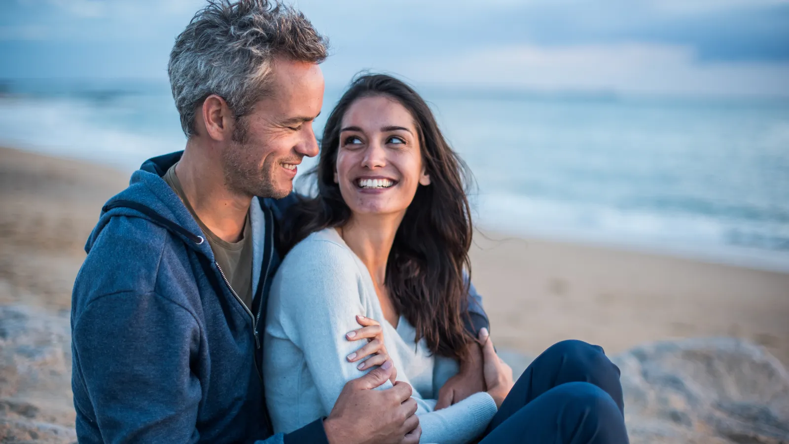 a man and woman sitting on a beach