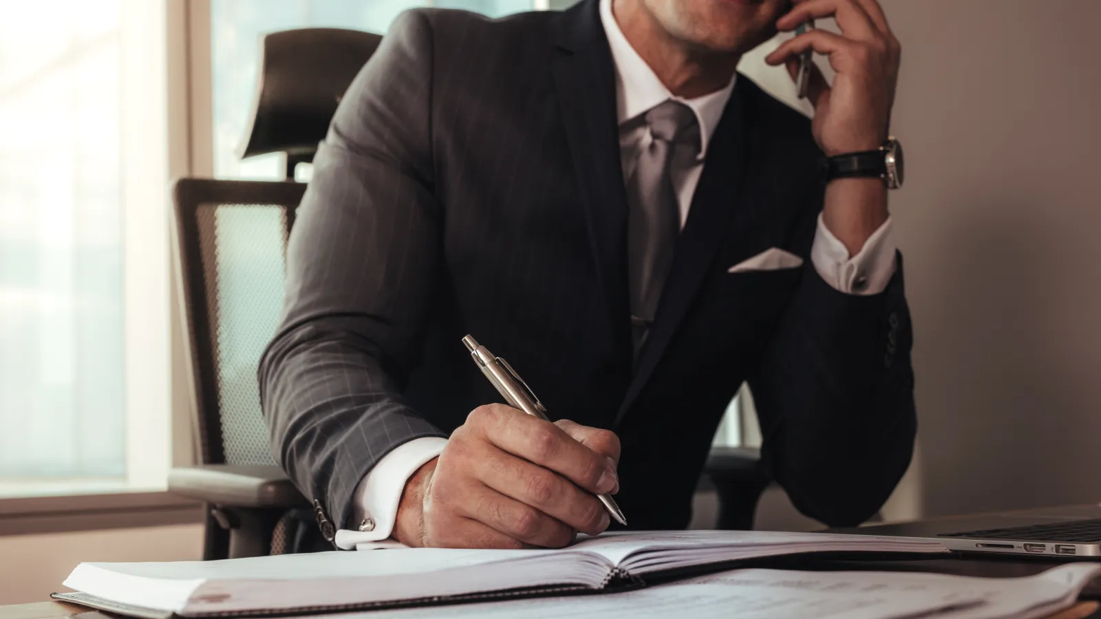 a man wearing a suit and tie sitting at a desk