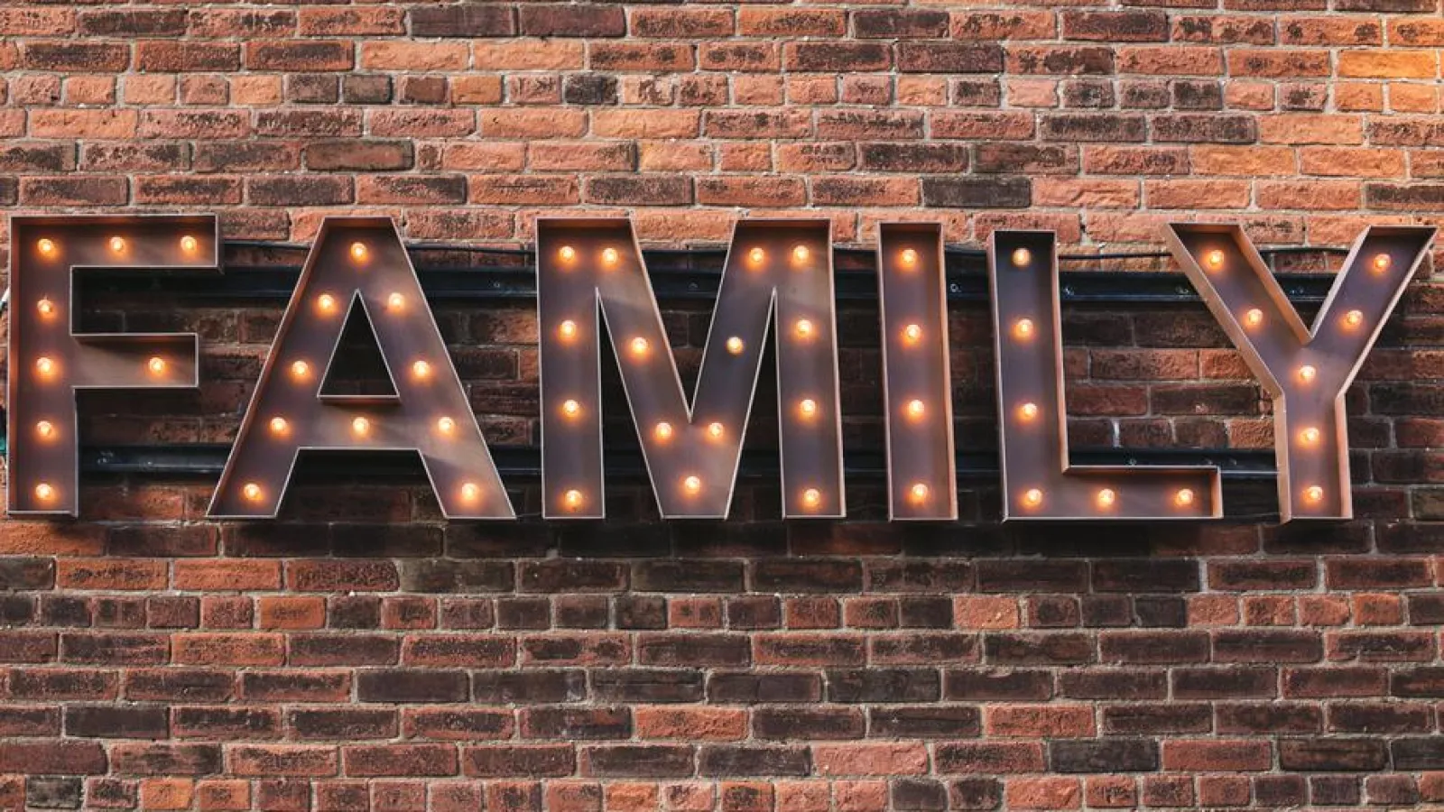 family sign hanging against brick wall