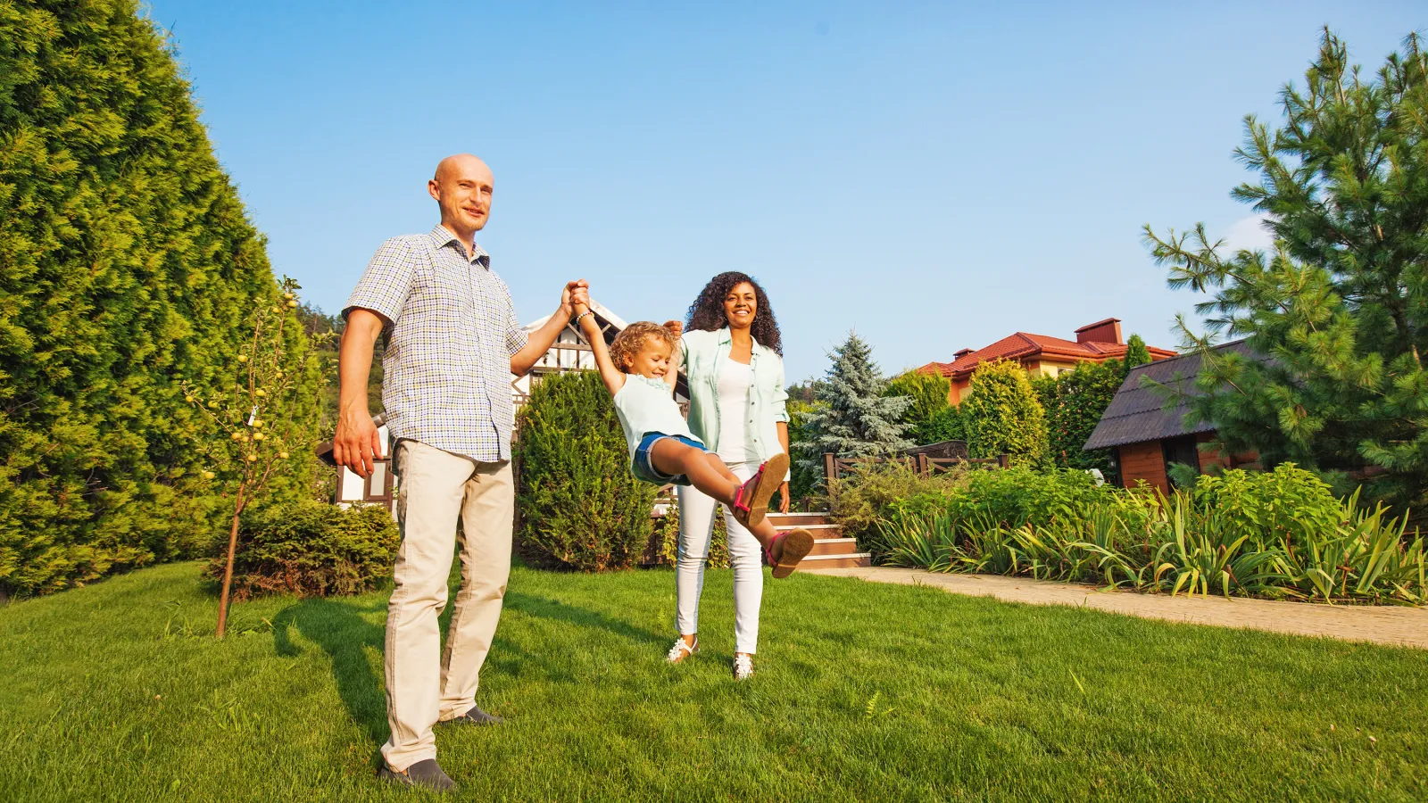 mom and dad swinging girl in lawn