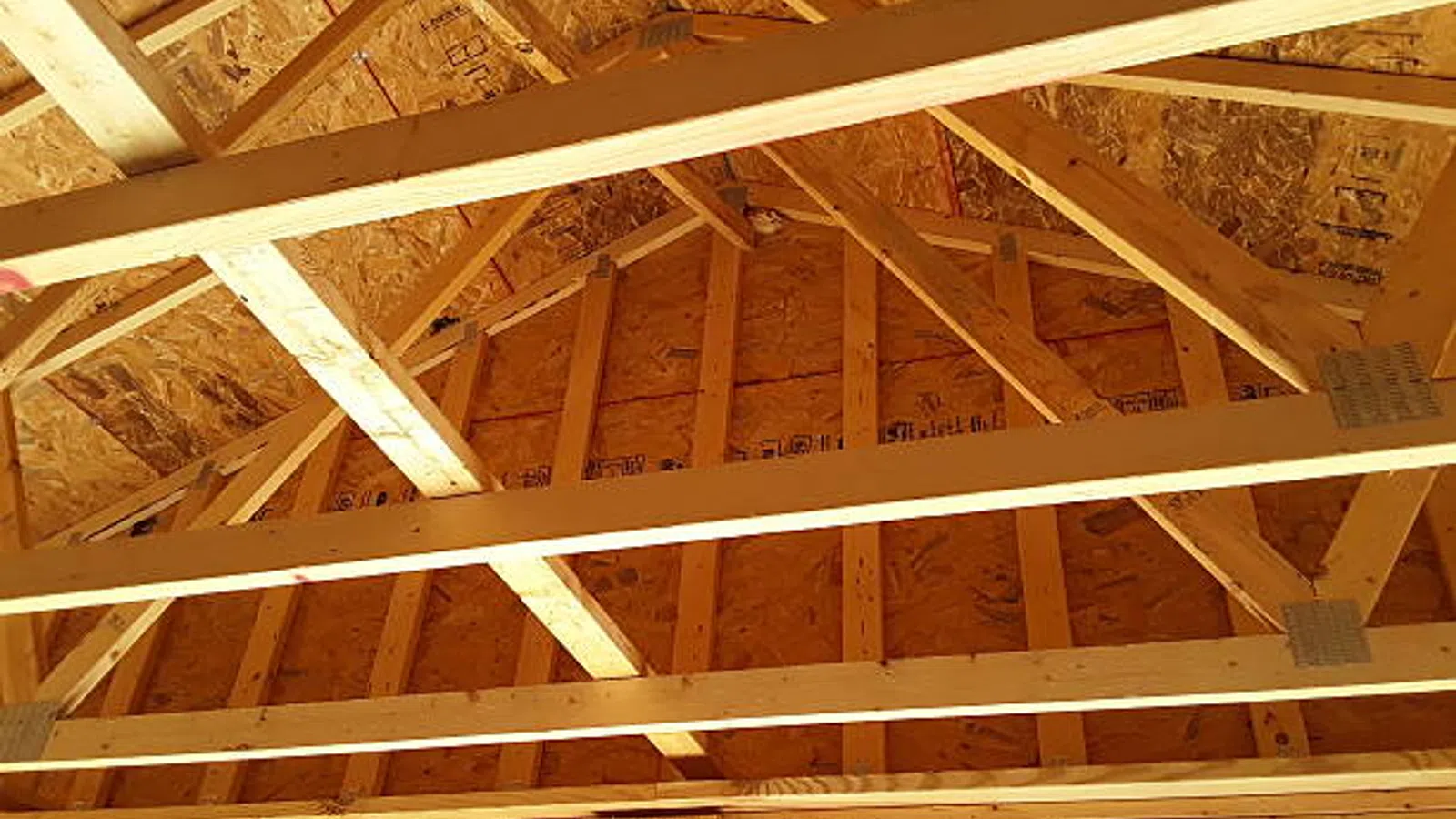 Wooden roof trusses and beams with oriented strand board sheathing in house construction.