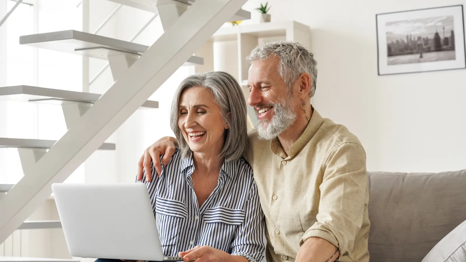 a man and a woman sitting on a couch looking at a computer