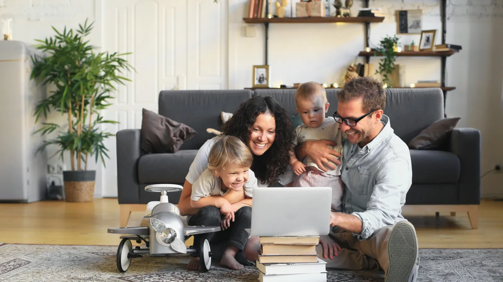 a family sitting on the floor with books and a laptop